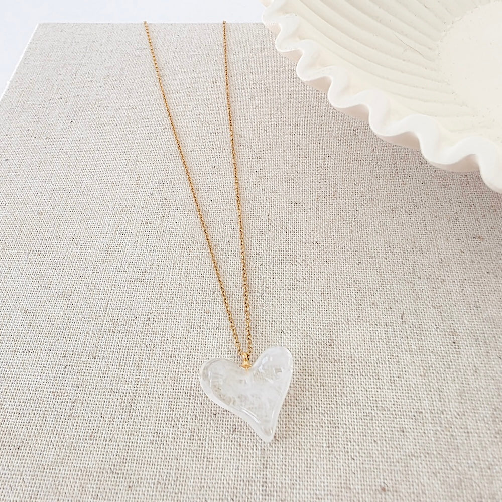 Clear resin heart pendant necklace on gold chain, close-up