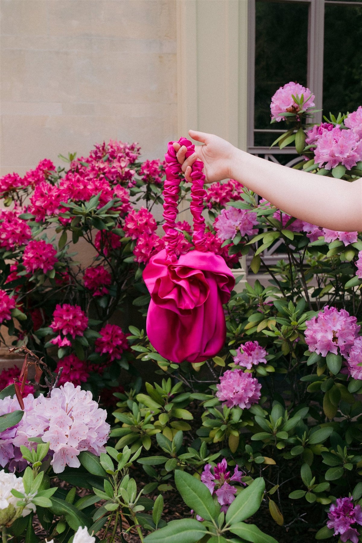 Fuchsia silk Bloom bag held by its gathered handle