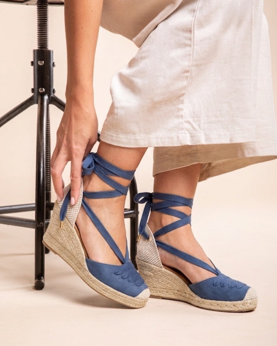 Blue lace-up espadrille wedges worn with ankle ties wrapped around the legs