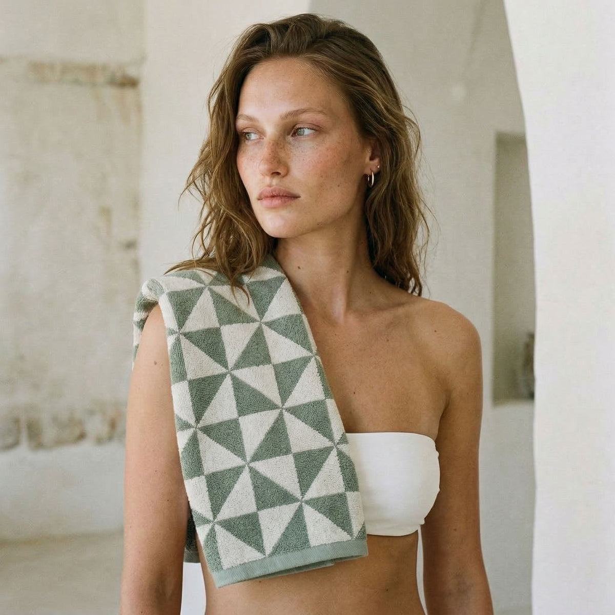 Geometric cotton towel draped over shoulder in sage green and ecru triangle pattern.