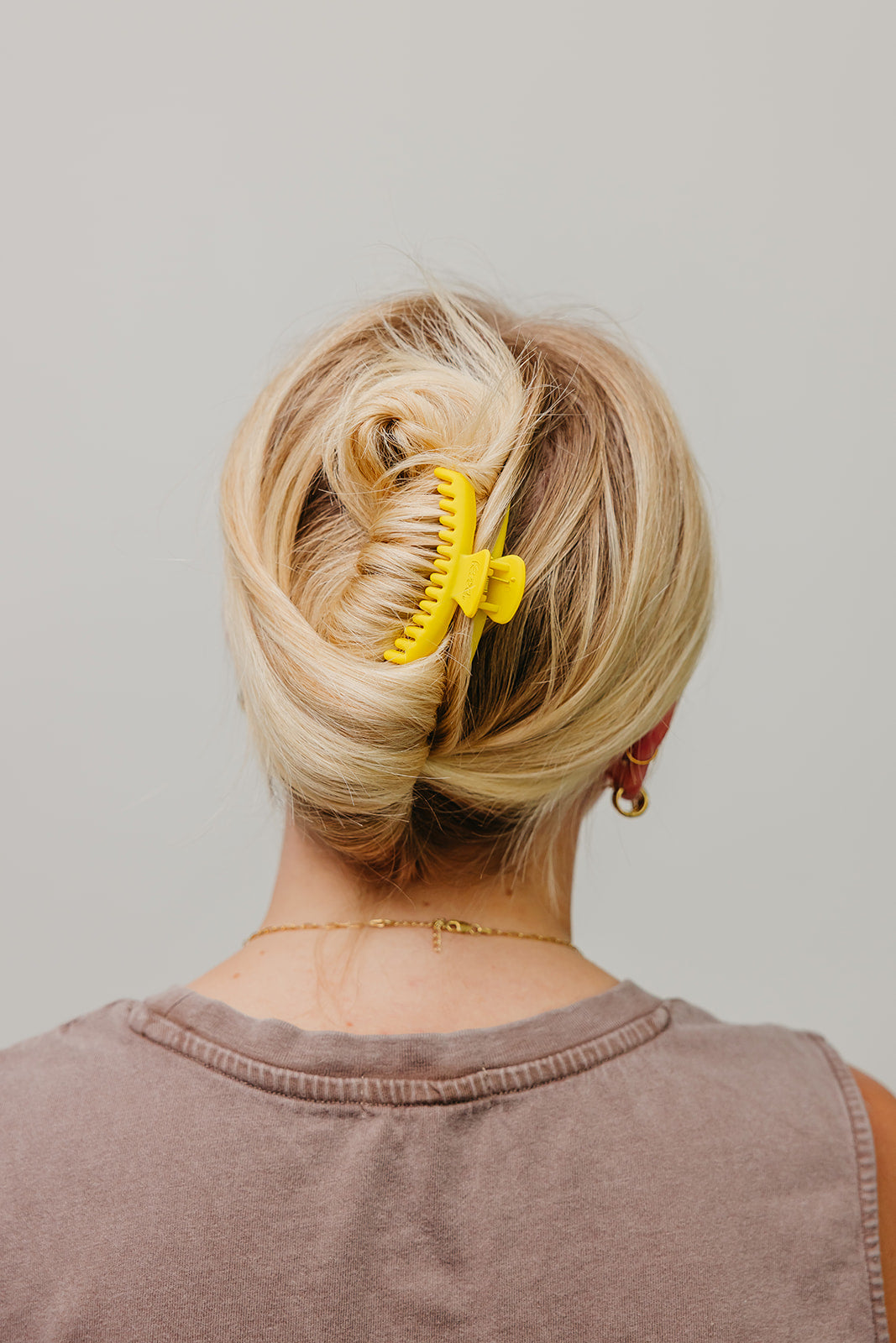 Matte mini hold-everything claw hair clip, yellow, holding blonde hair up in a bun