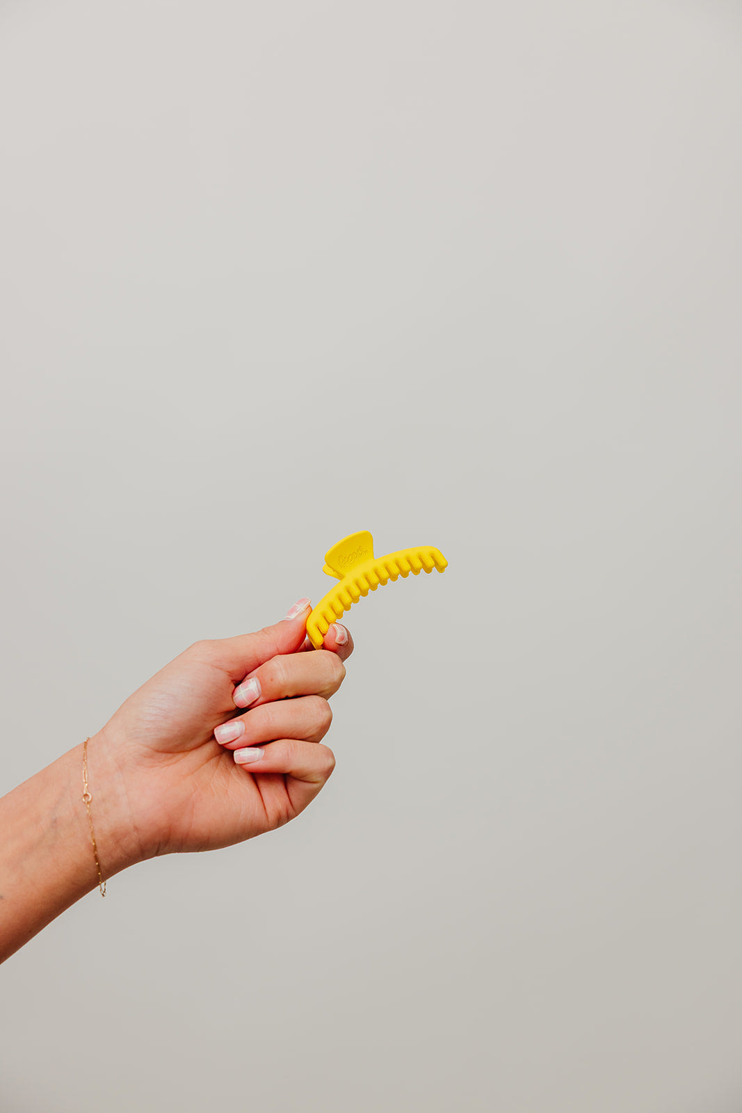 Matte mini hold-everything claw hair clip in bright yellow held in hand