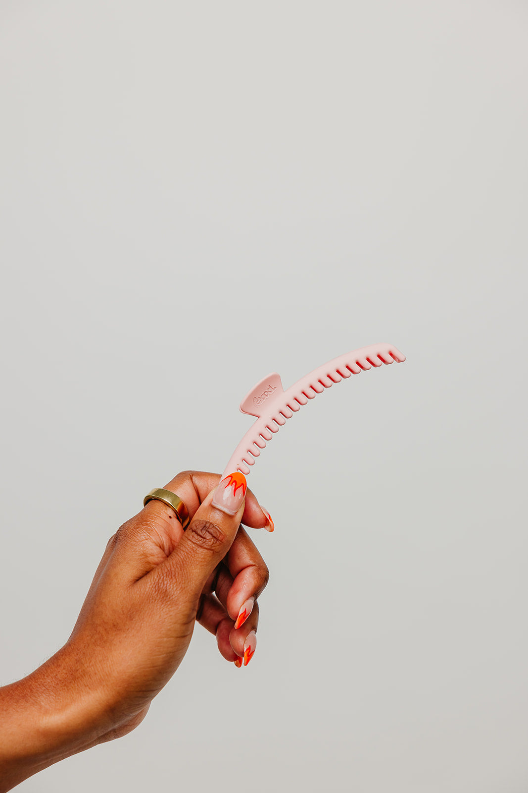 Pink hair claw clip held in hand with serrated grip teeth