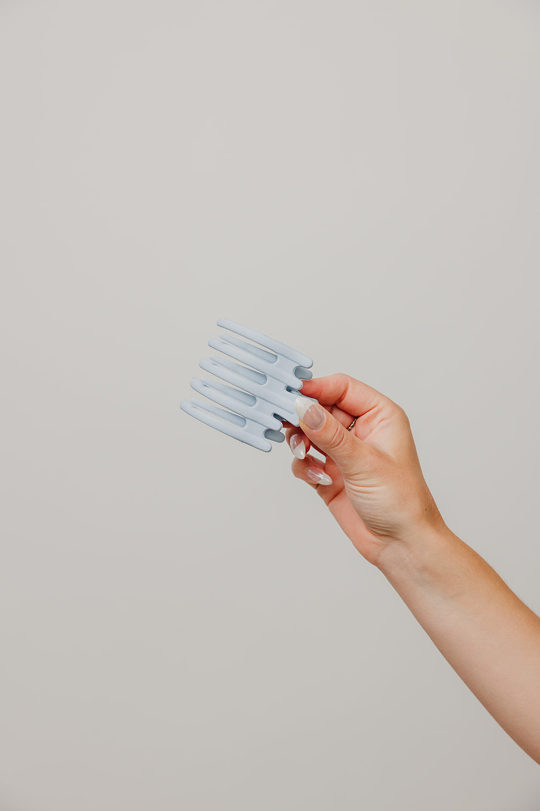 Hair claw clip in light blue held in a hand
