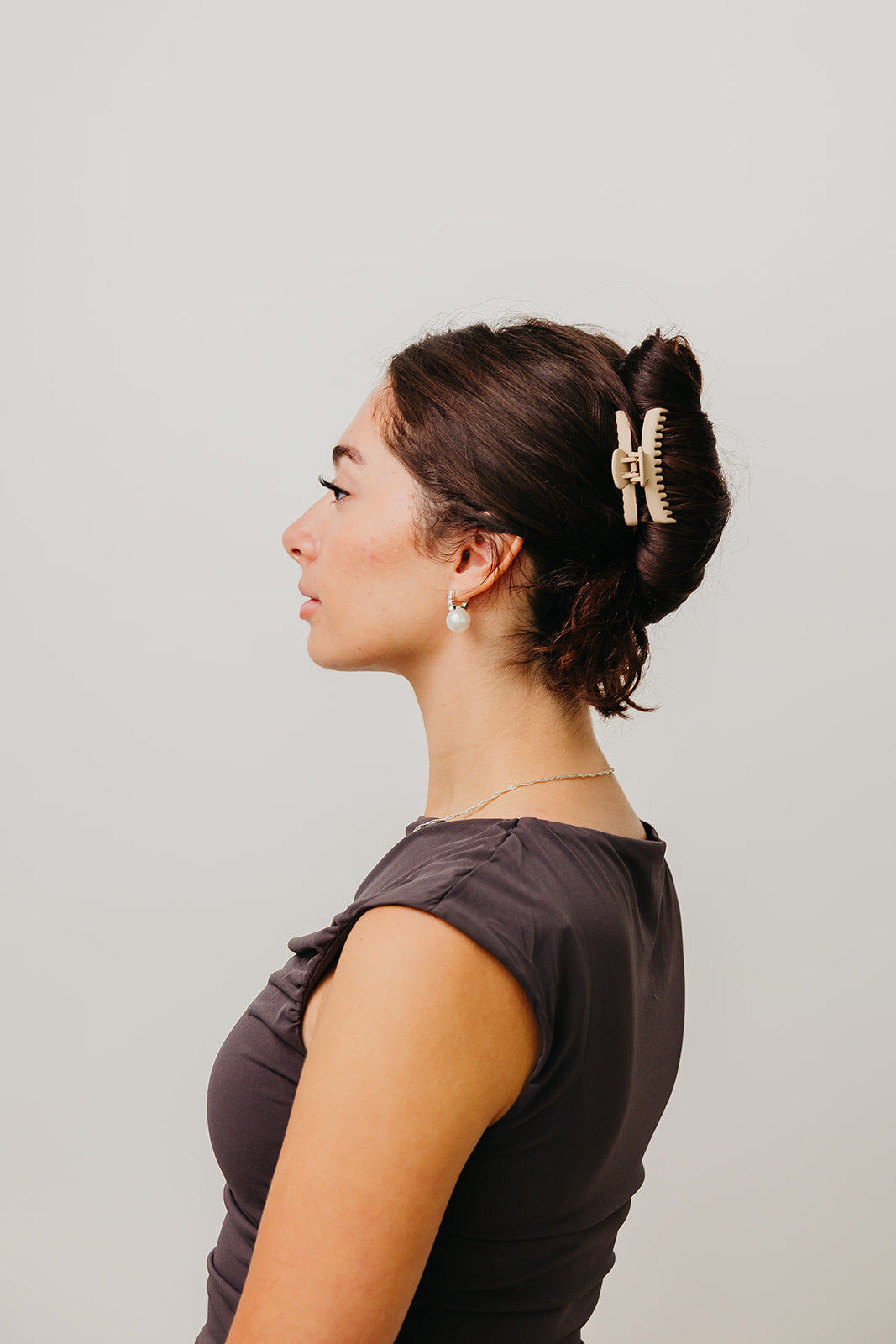 Mini matte hair claw clip securing dark brown hair bun on side profile