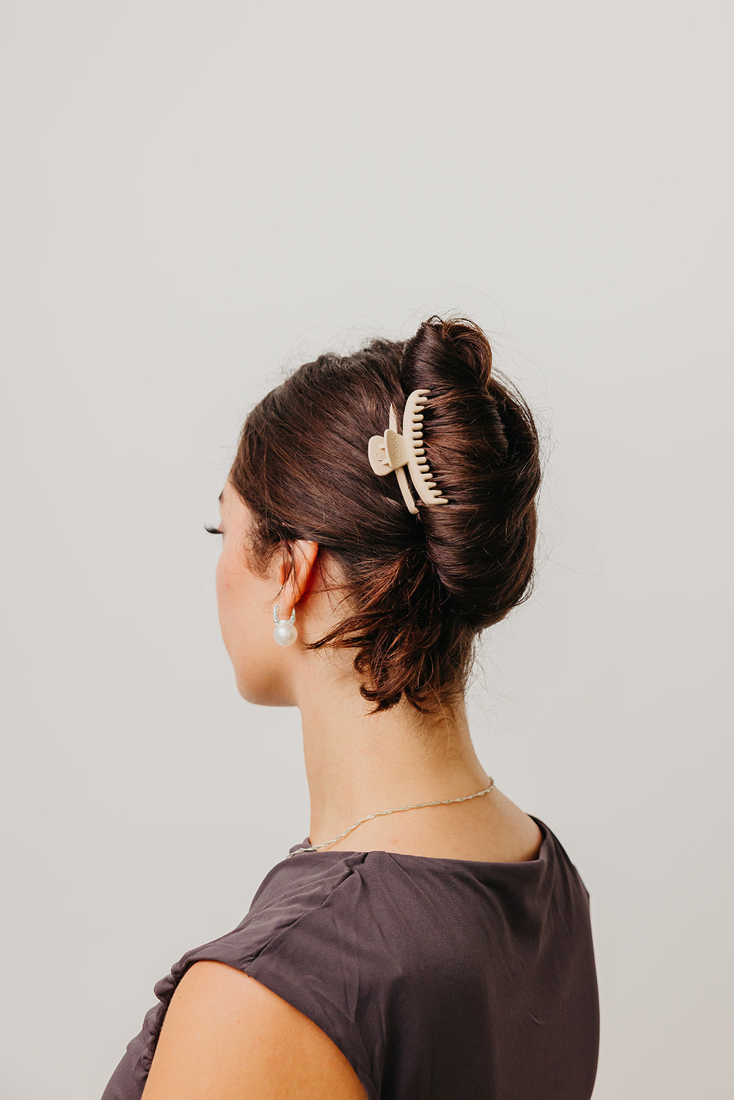 Mini matte hair claw clip holding dark brown hair bun