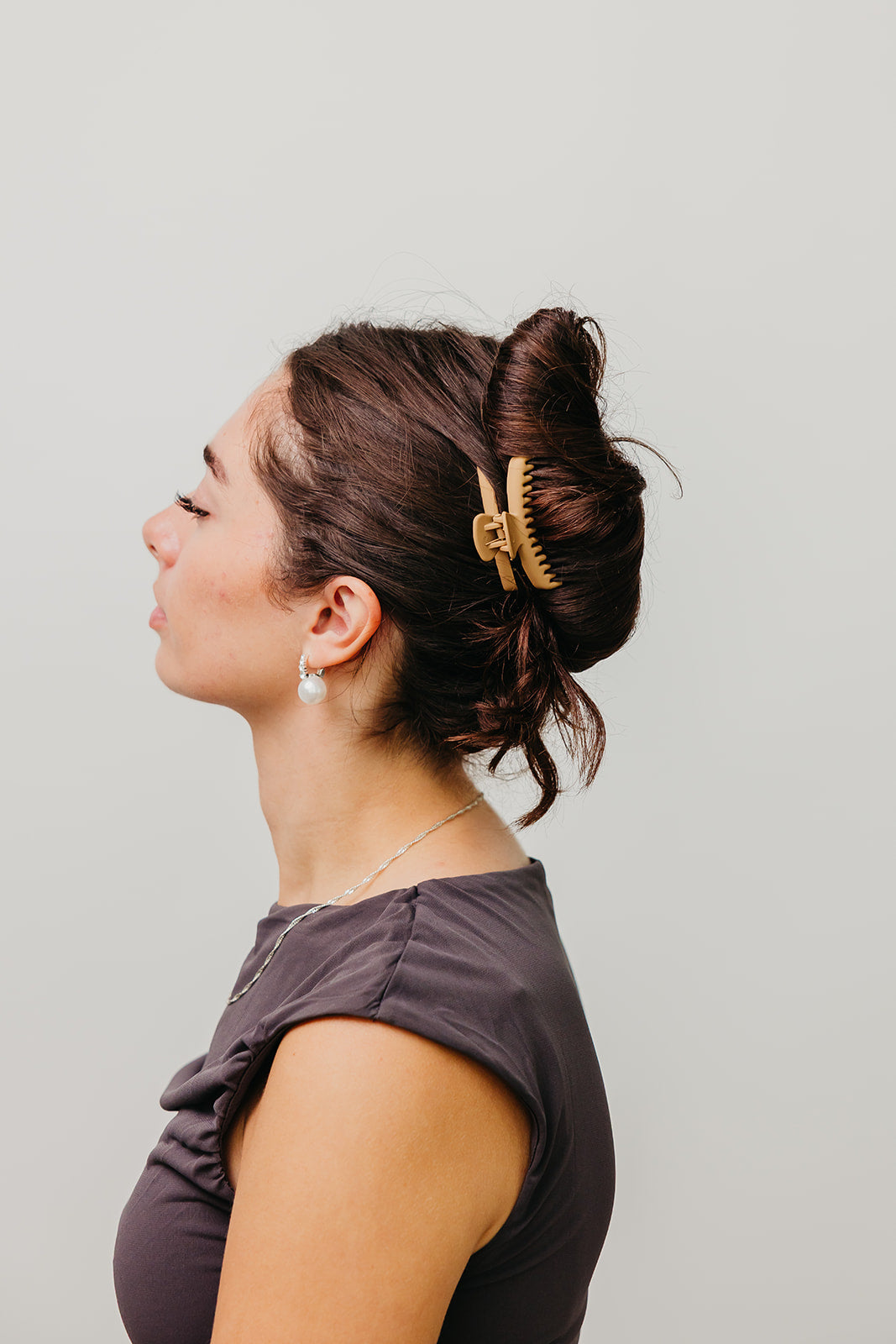 Mini matte hair claw securing dark brown hair in a bun