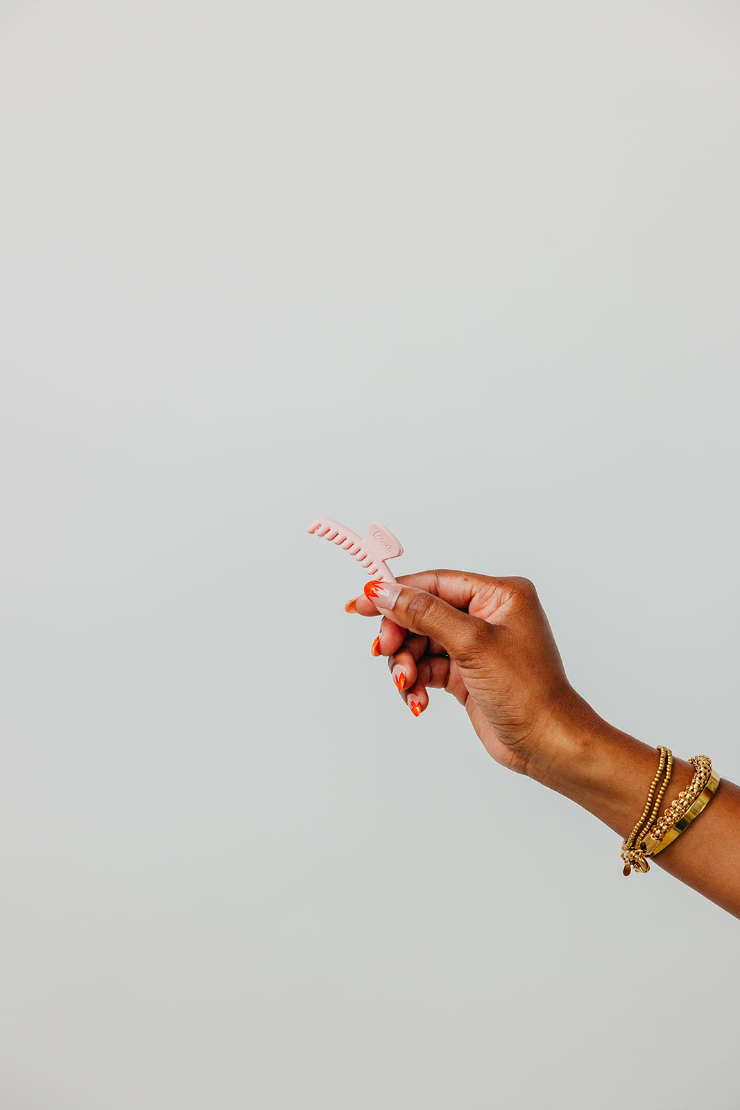 Orange matte mini claw hair clip held in a hand.