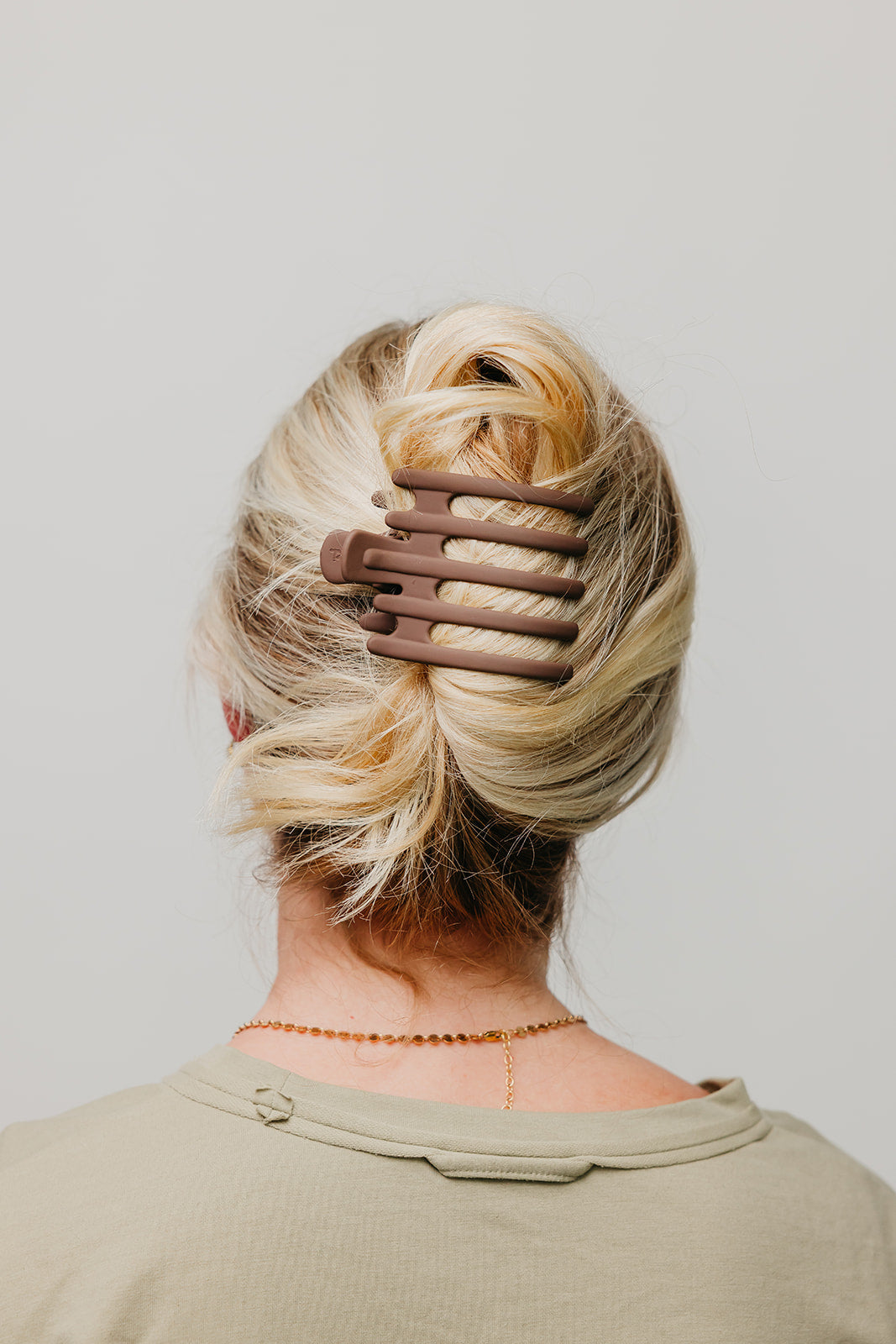 Hair claw clip in dark brown gripping blonde hair bun