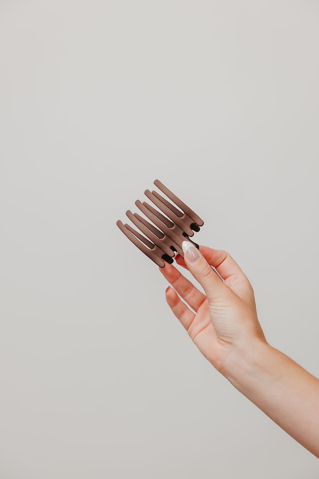Hair claw clip in dark brown held by a hand