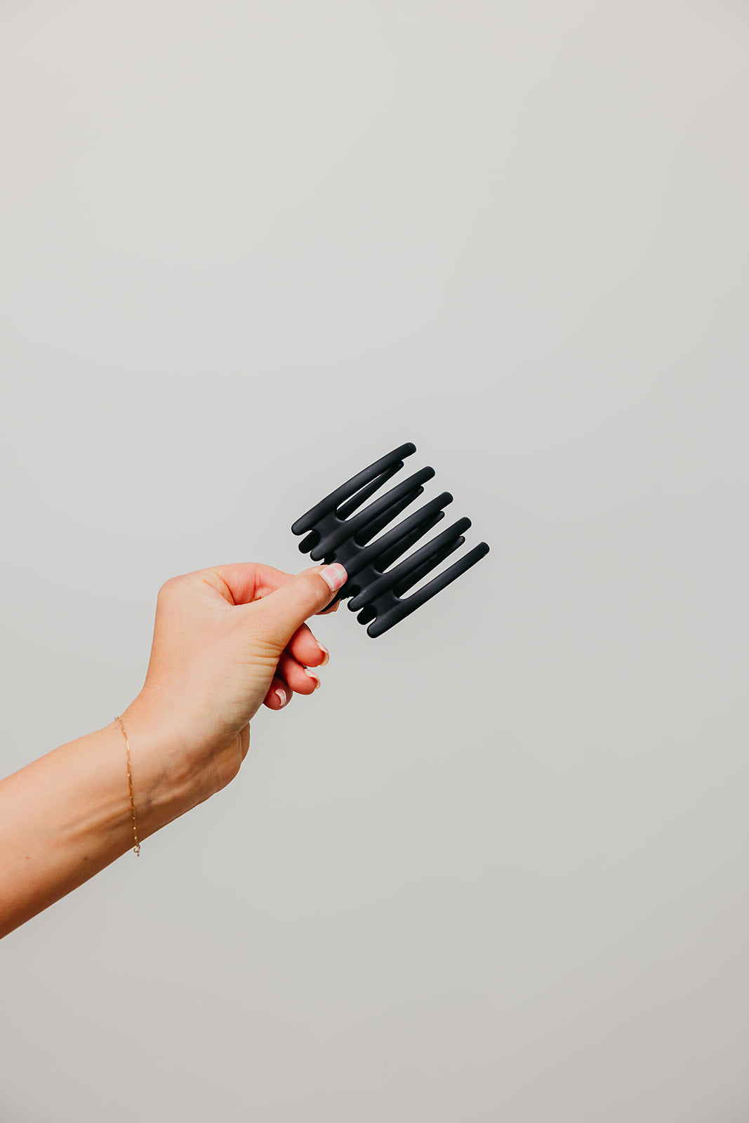 Hair claw clip in matte black held in a hand