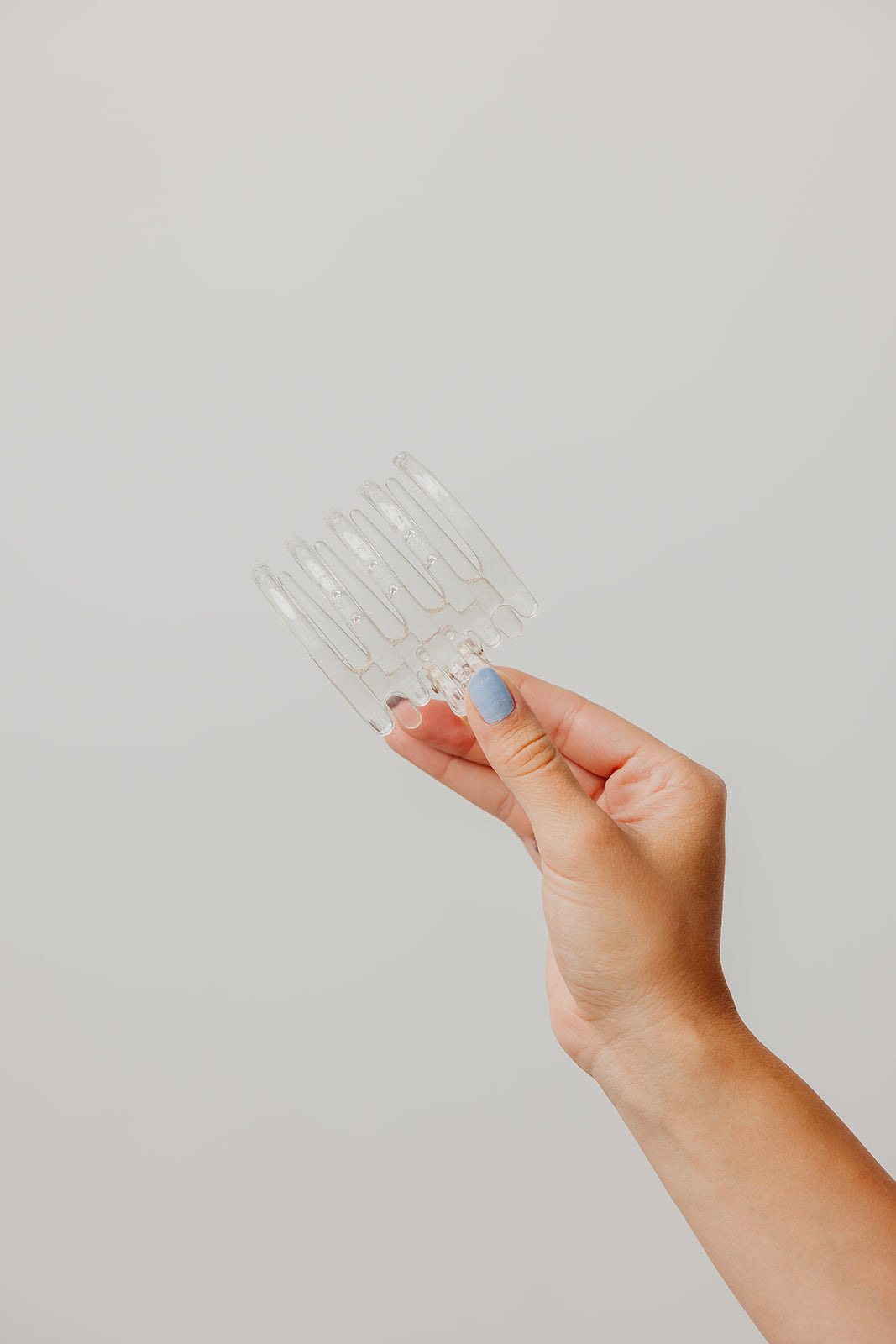 Clear wide hair claw clip held in hand, sculpted teeth