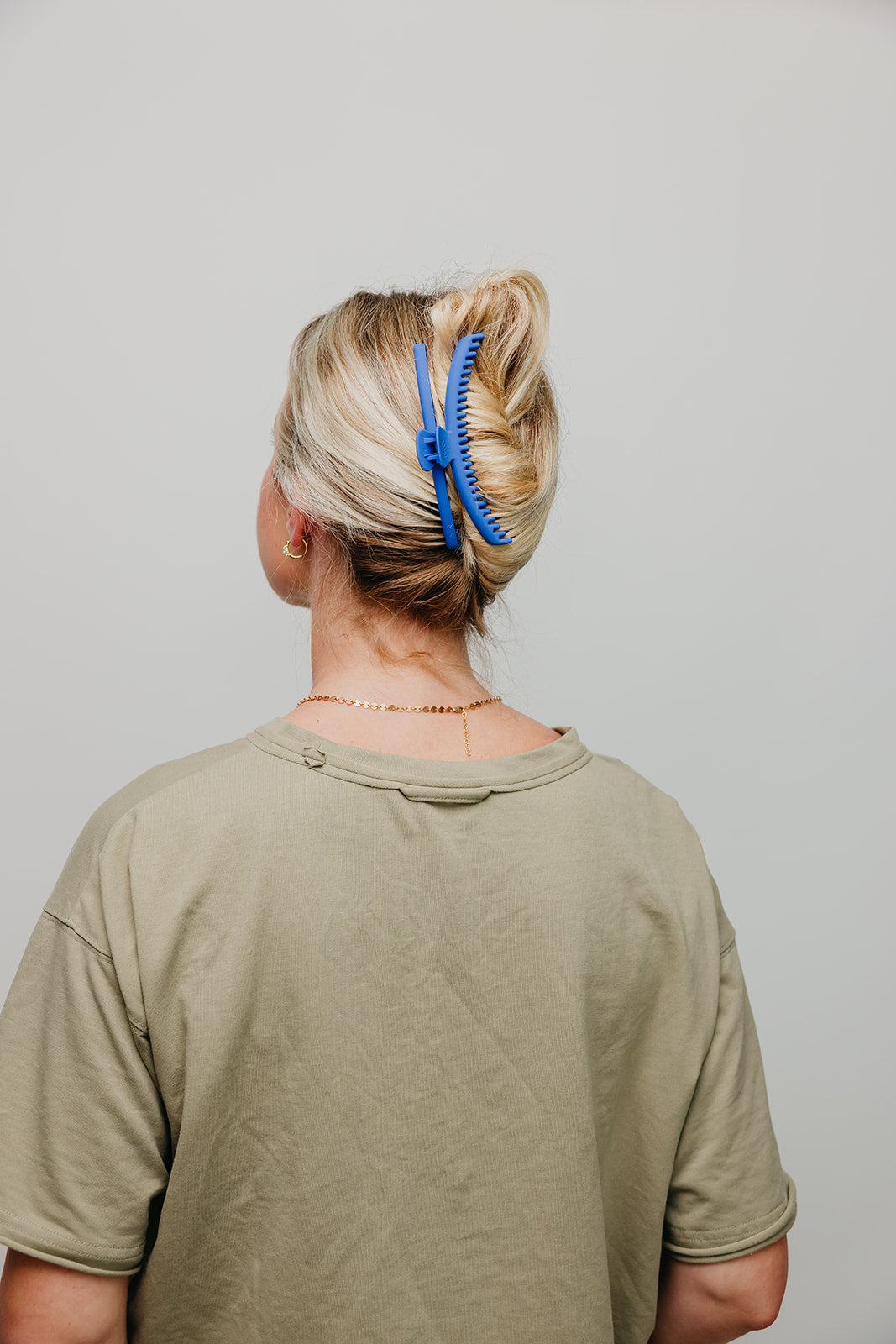 Blue matte claw hair clip in blonde hair bun, rear view