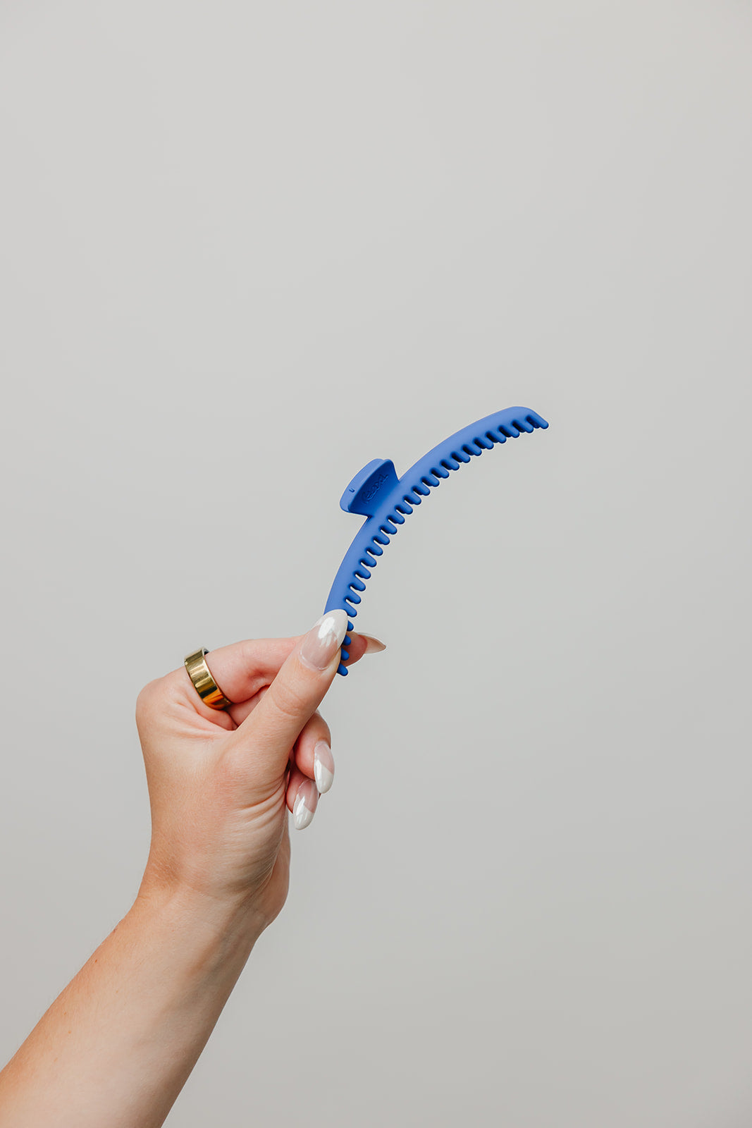 Bright blue matte claw hair clip held by the handle