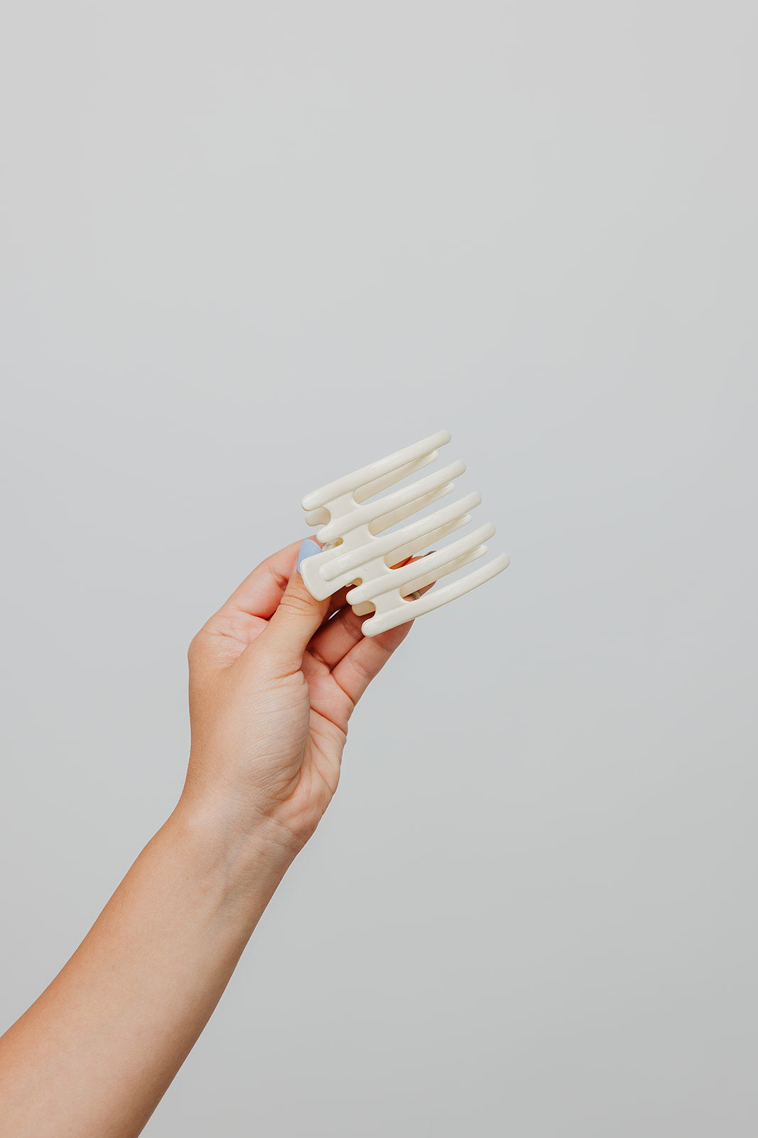 Wide laydown claw hair clip in hand, translucent ivory finish