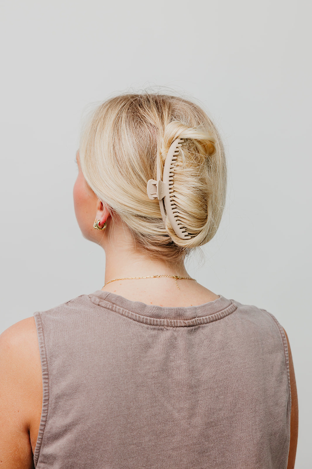 Matte hair claw clip in blonde hair, side/back view, holding hair up; mauve sleeveless top.