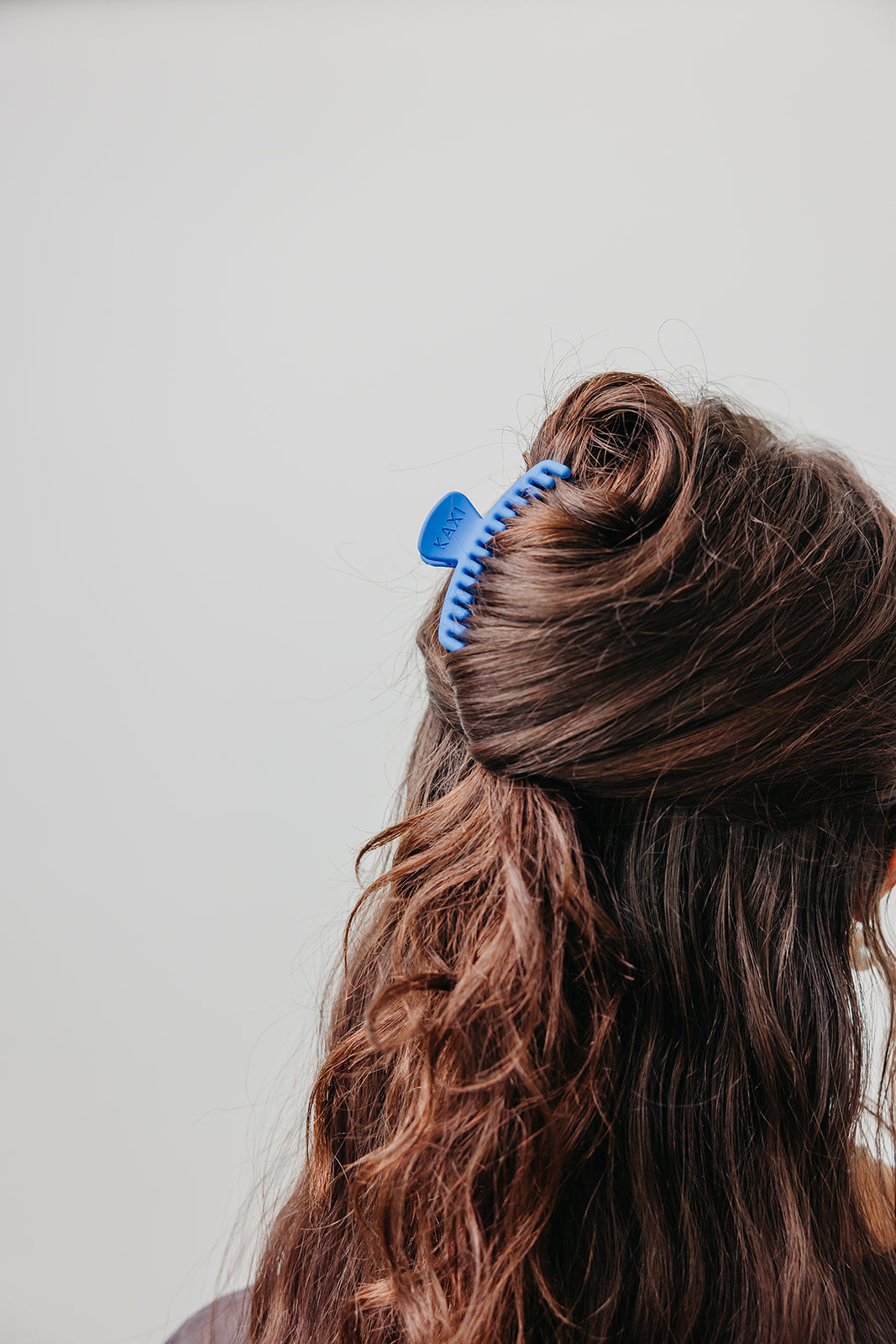 Matte mini claw hair clip, blue, holding brown hair in a bun