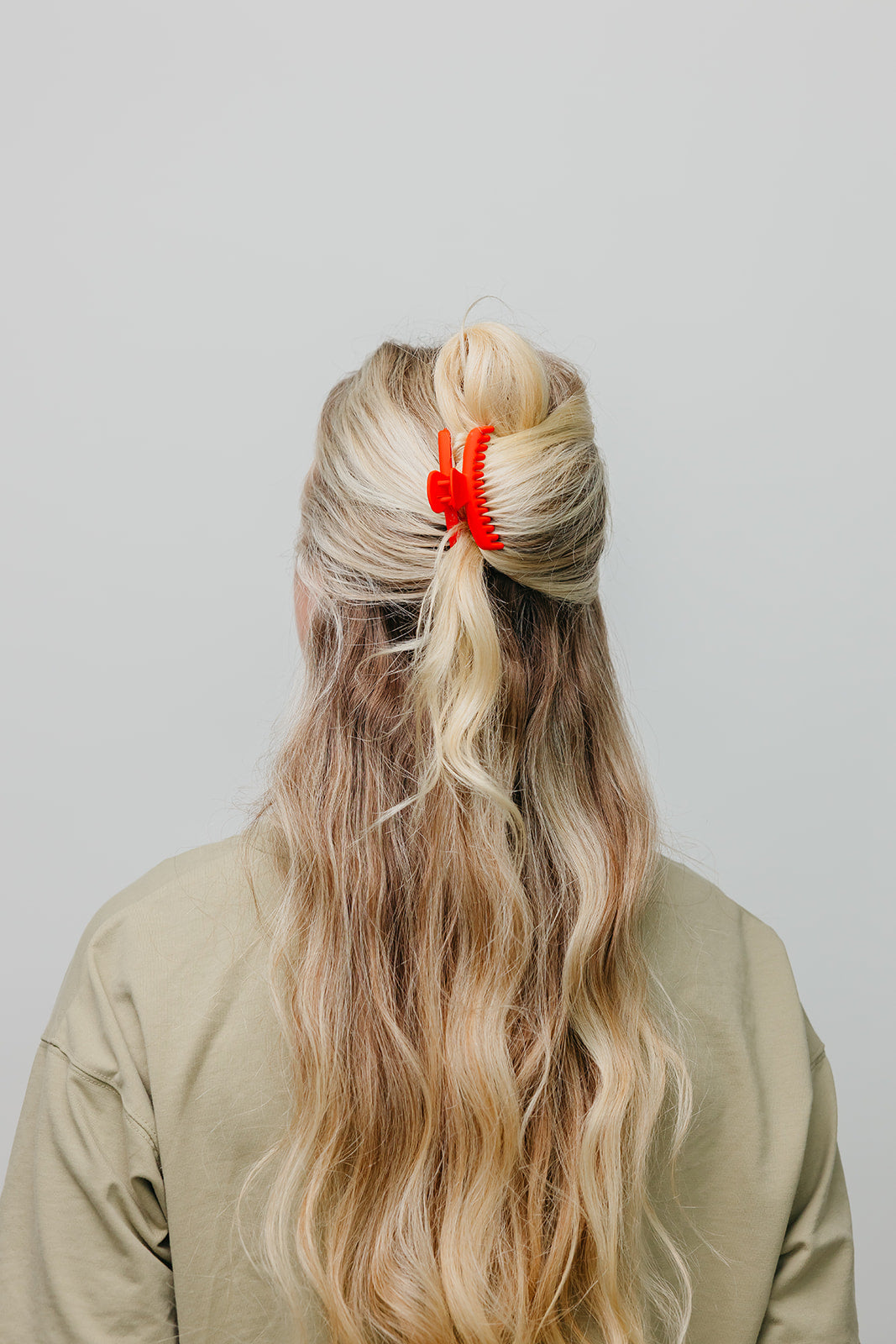 Red matte mini claw hair clip holding blonde hair up at the back.