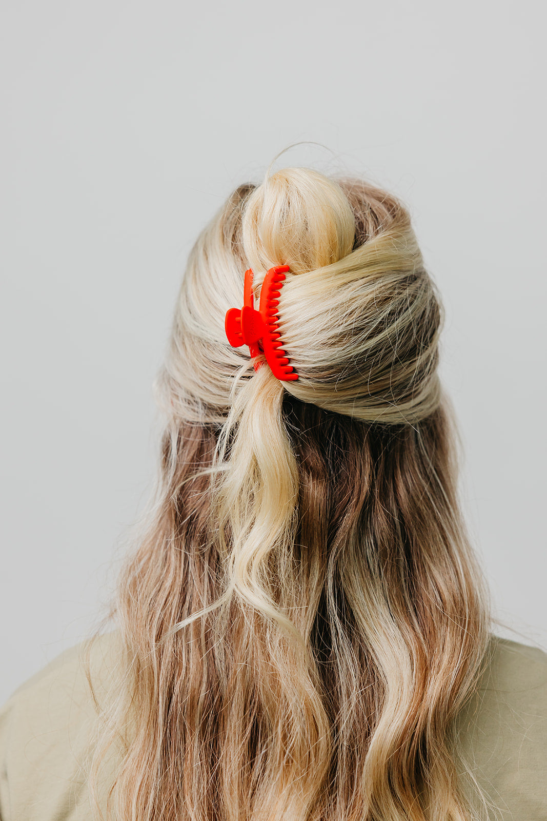 Red matte mini claw hair clip securing blonde hair back.