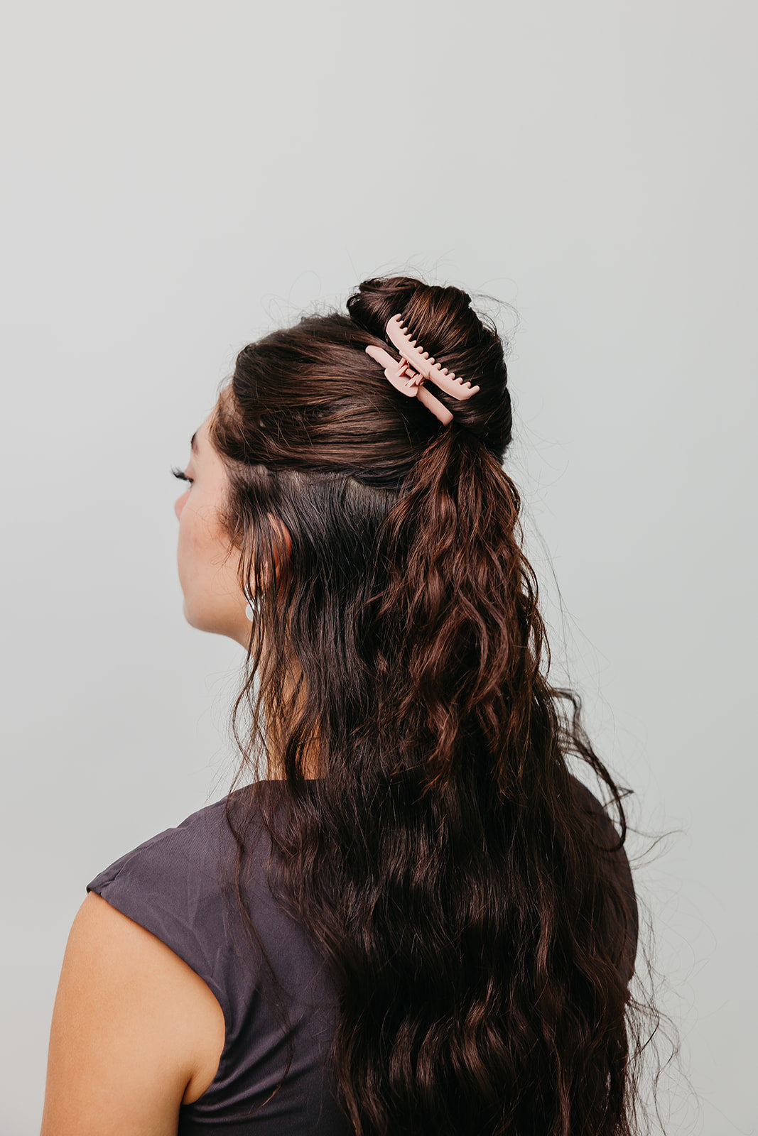 Mini matte hair claw clip securing dark brown hair in a bun