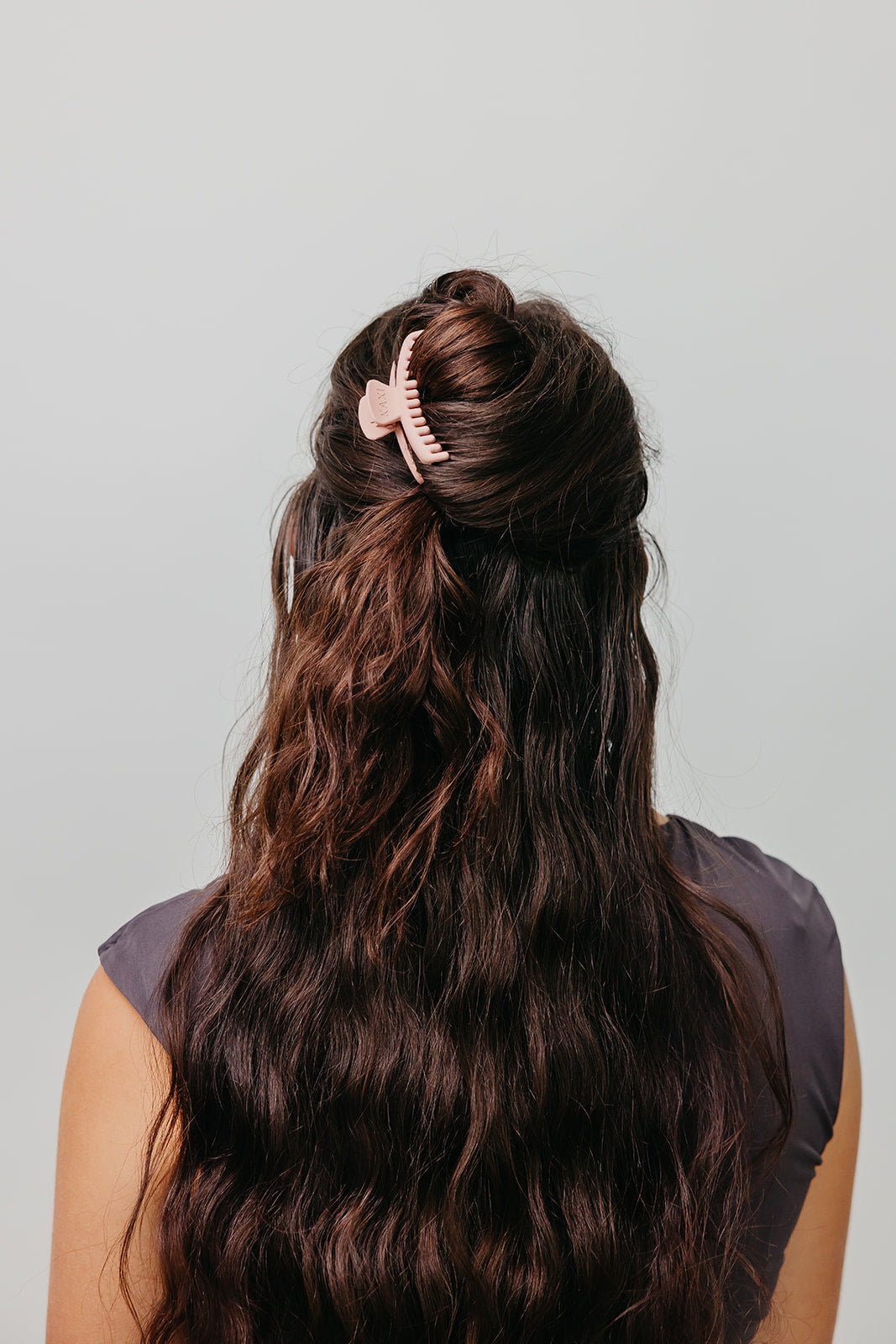 Mini matte hair claw securing long dark brown hair bun