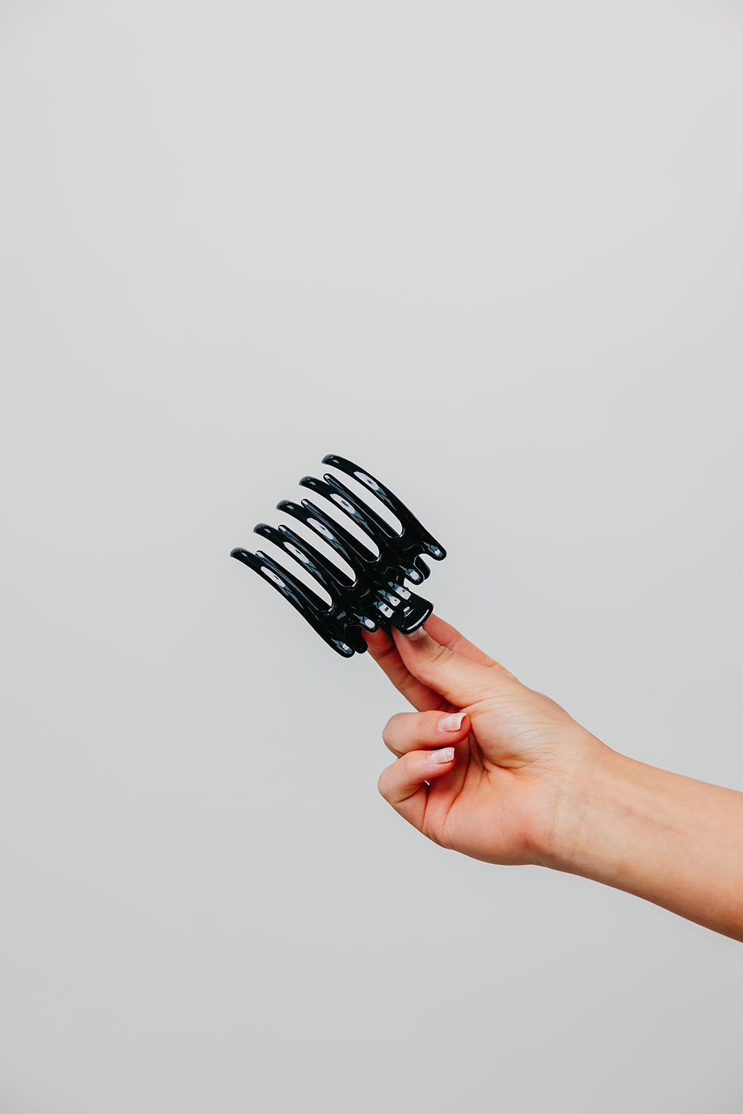 Wide laydown claw hair clip in hand, shiny black finish