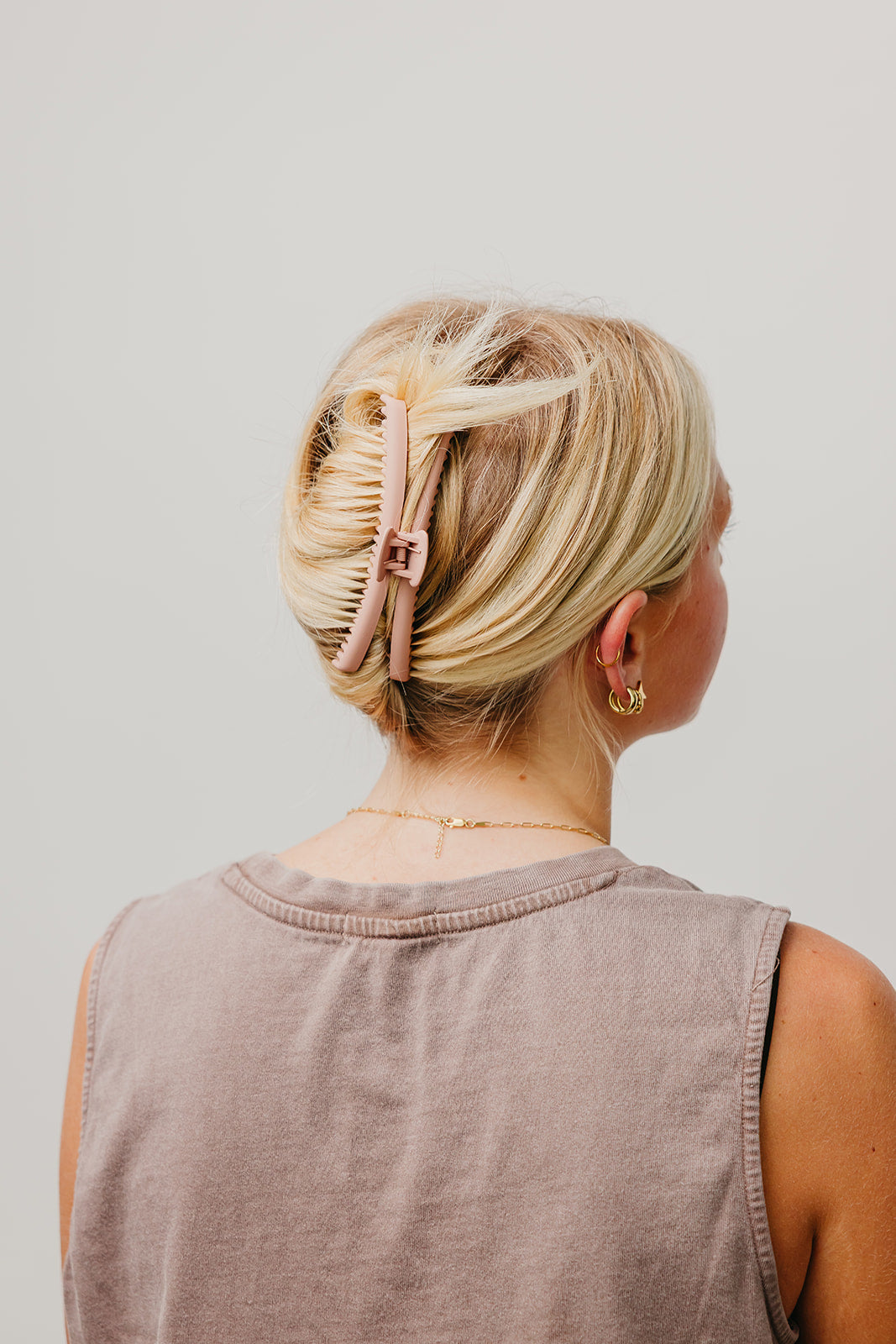 Matte hair claw clip in blonde hair, back view, holding hair up; mauve sleeveless top.