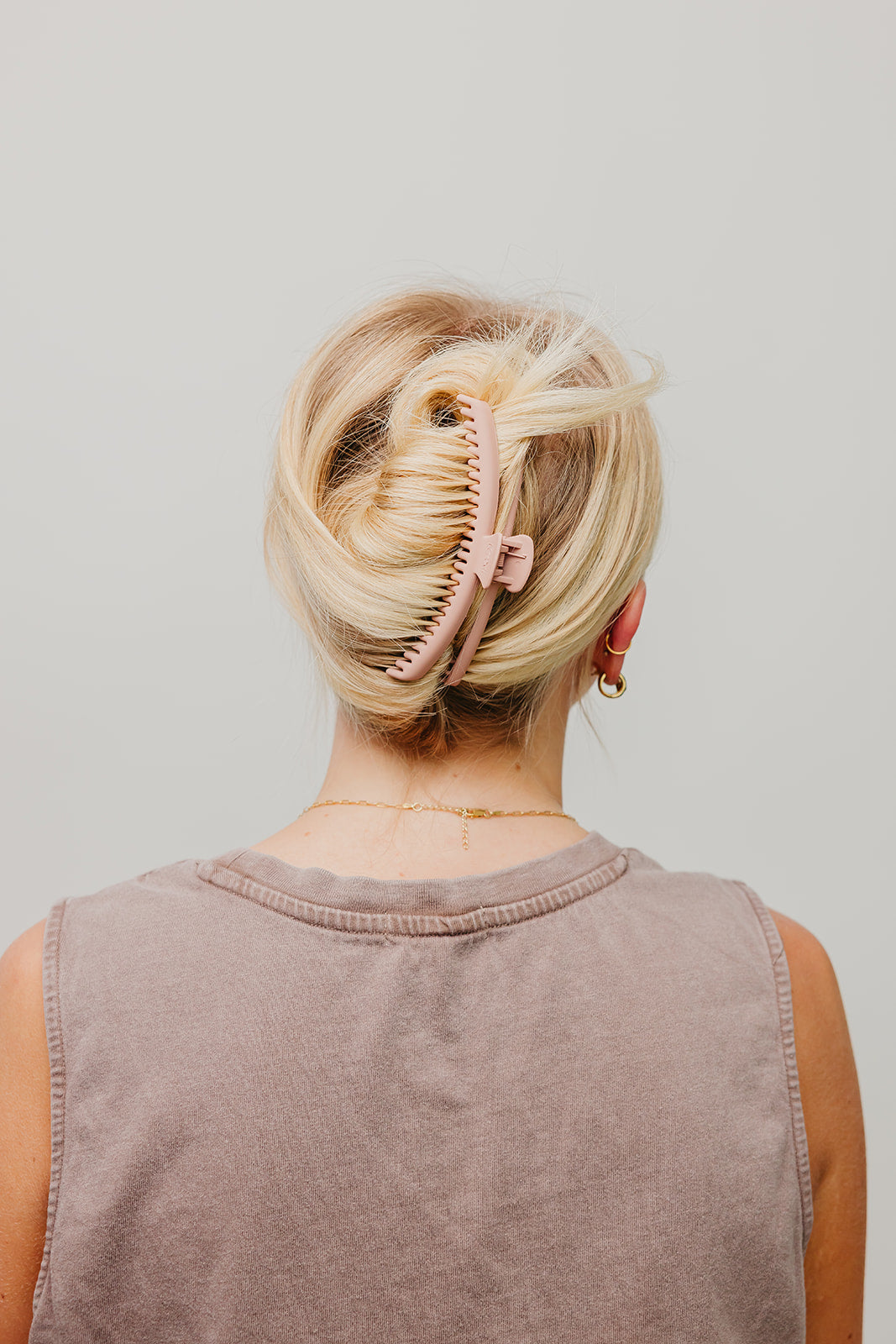 Matte hair claw clip in blonde hair, side view, holding hair up; dusty mauve top.