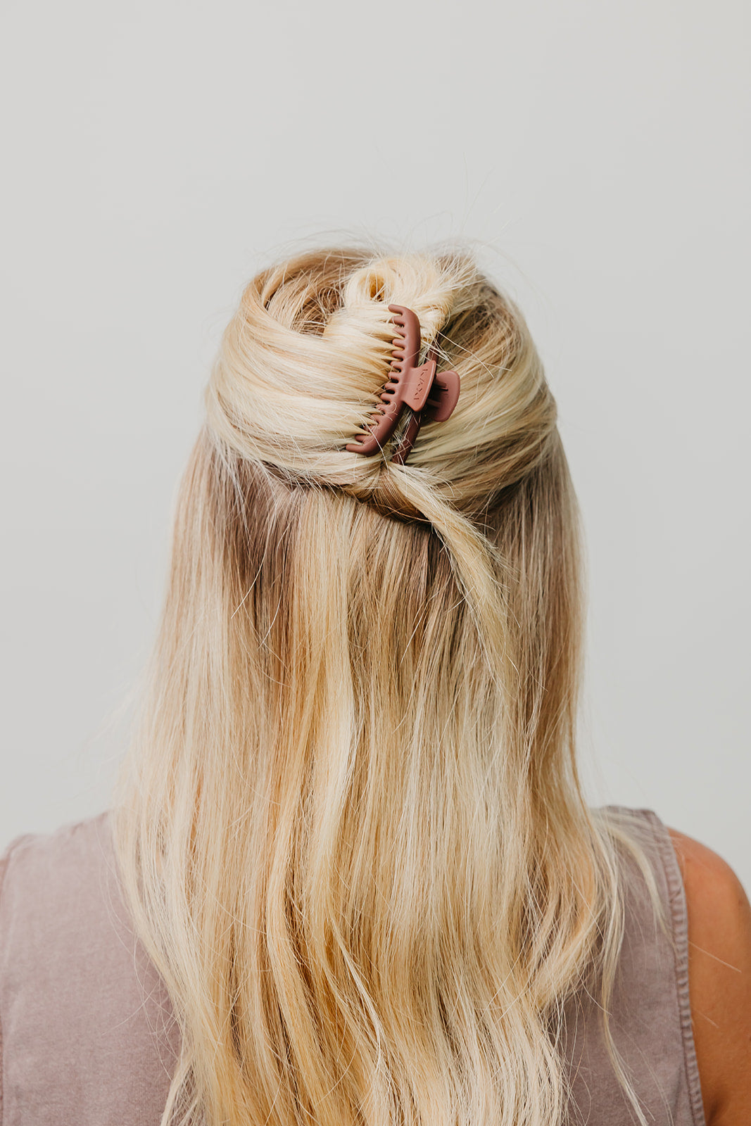 Brown matte claw hair clip holding long blonde hair in a half-up style.