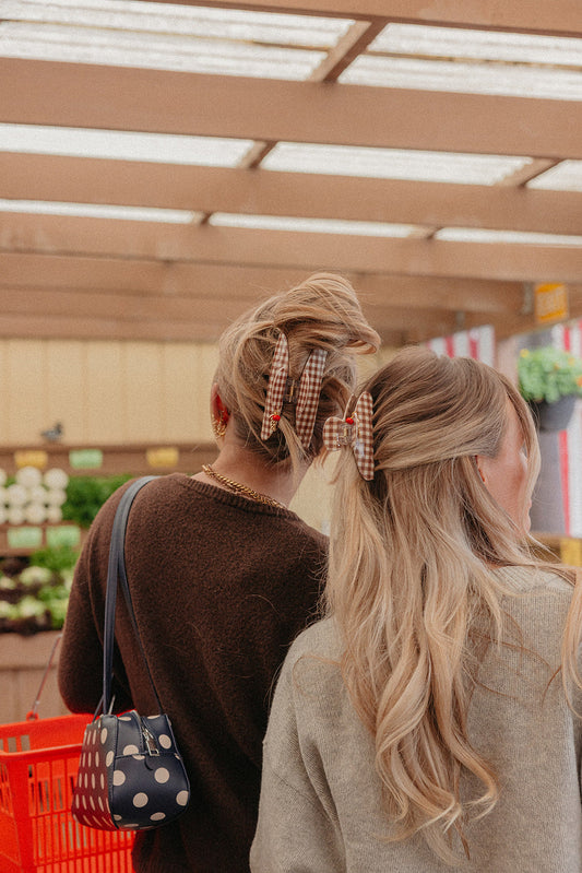 Brown gingham hair claw with small red tomato charm on blonde hair