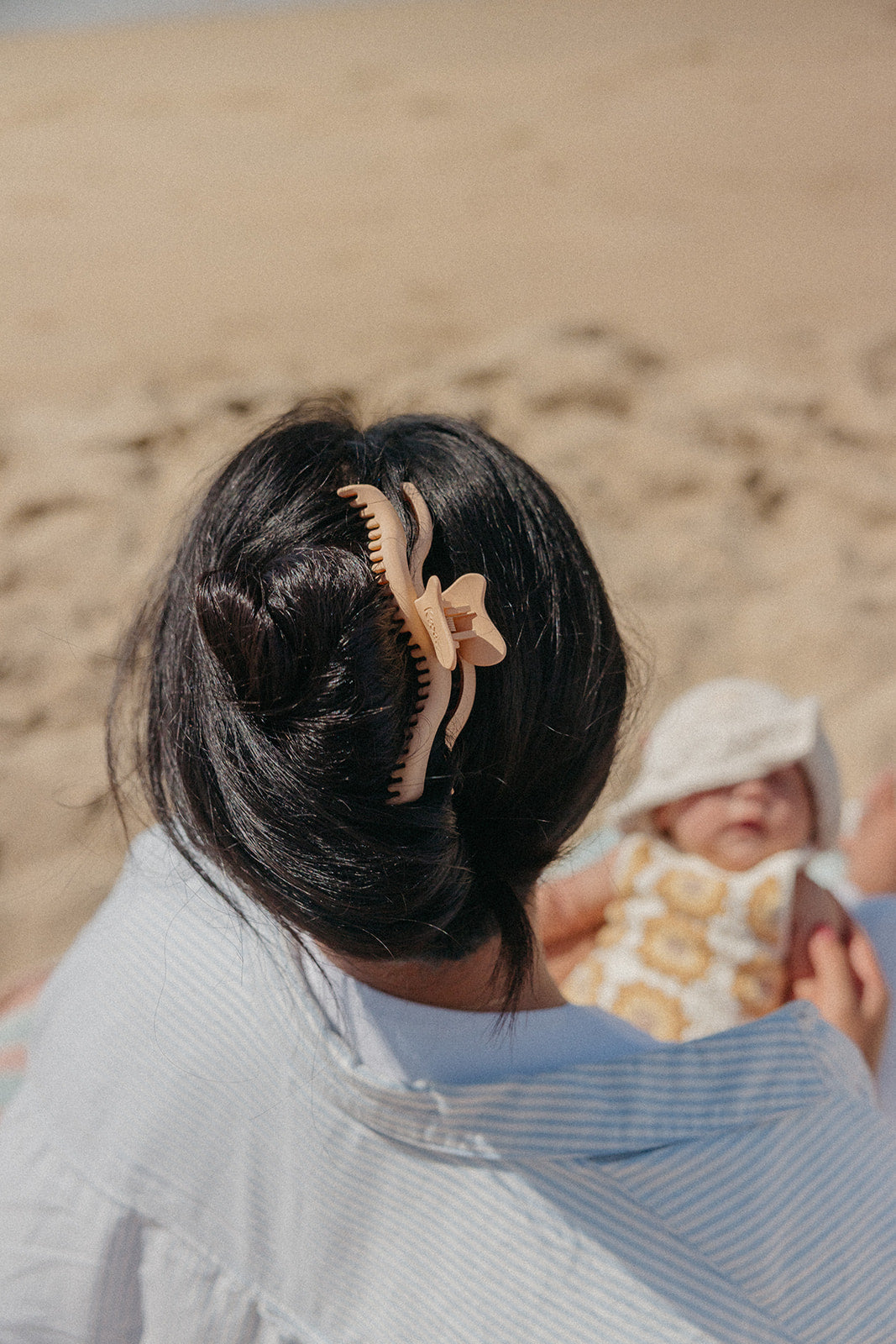 Black hair claw clip with comb teeth holding hair in a bun.