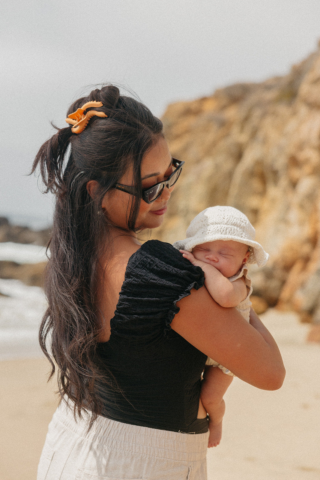 Wavy hair claw clip in warm orange, holding dark hair while holding a baby
