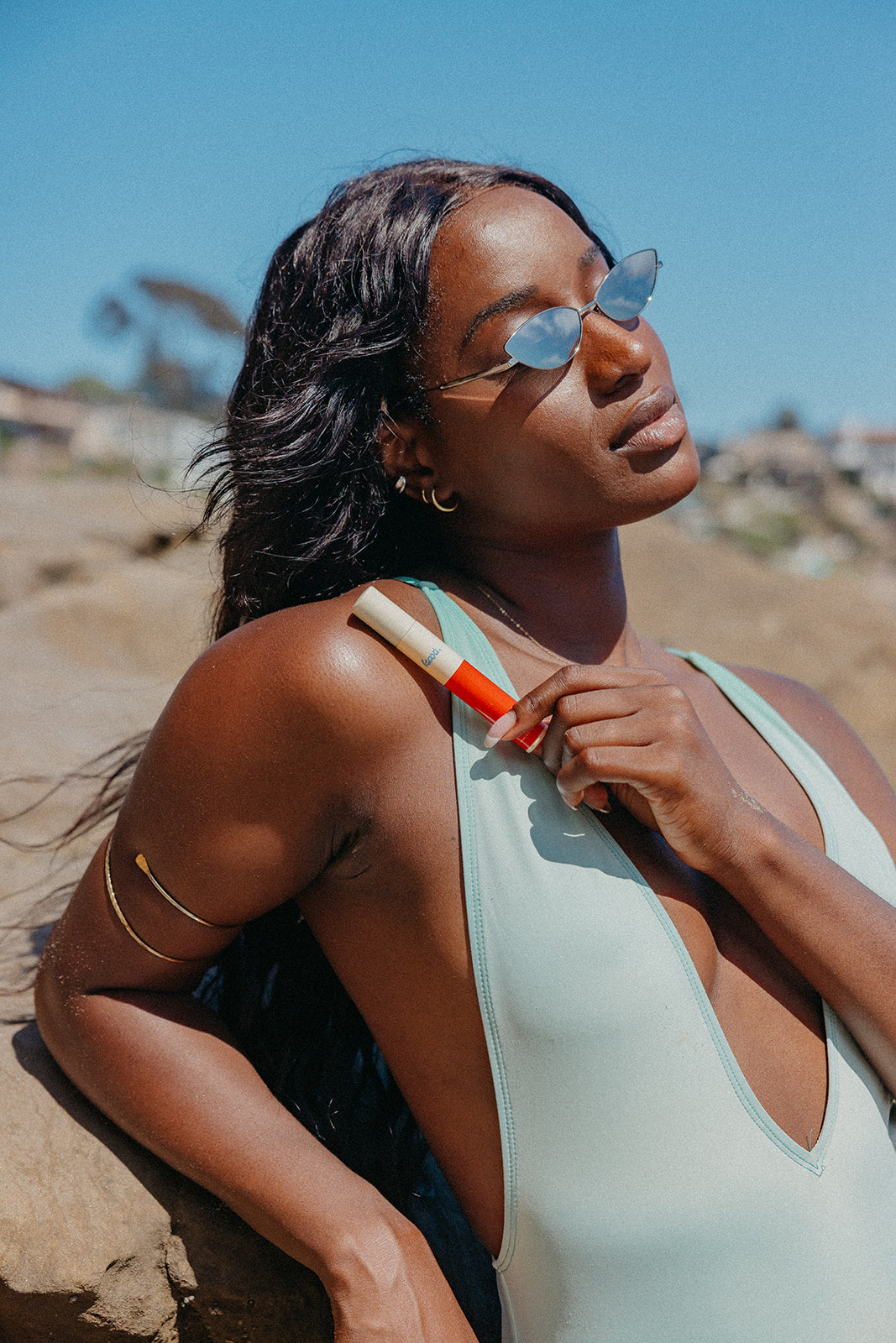 Woman holding a hair perfume spray near her hair in an outdoor setting