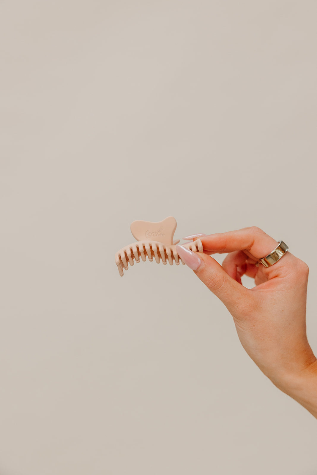 Nude wavy mini hair claw held between fingers