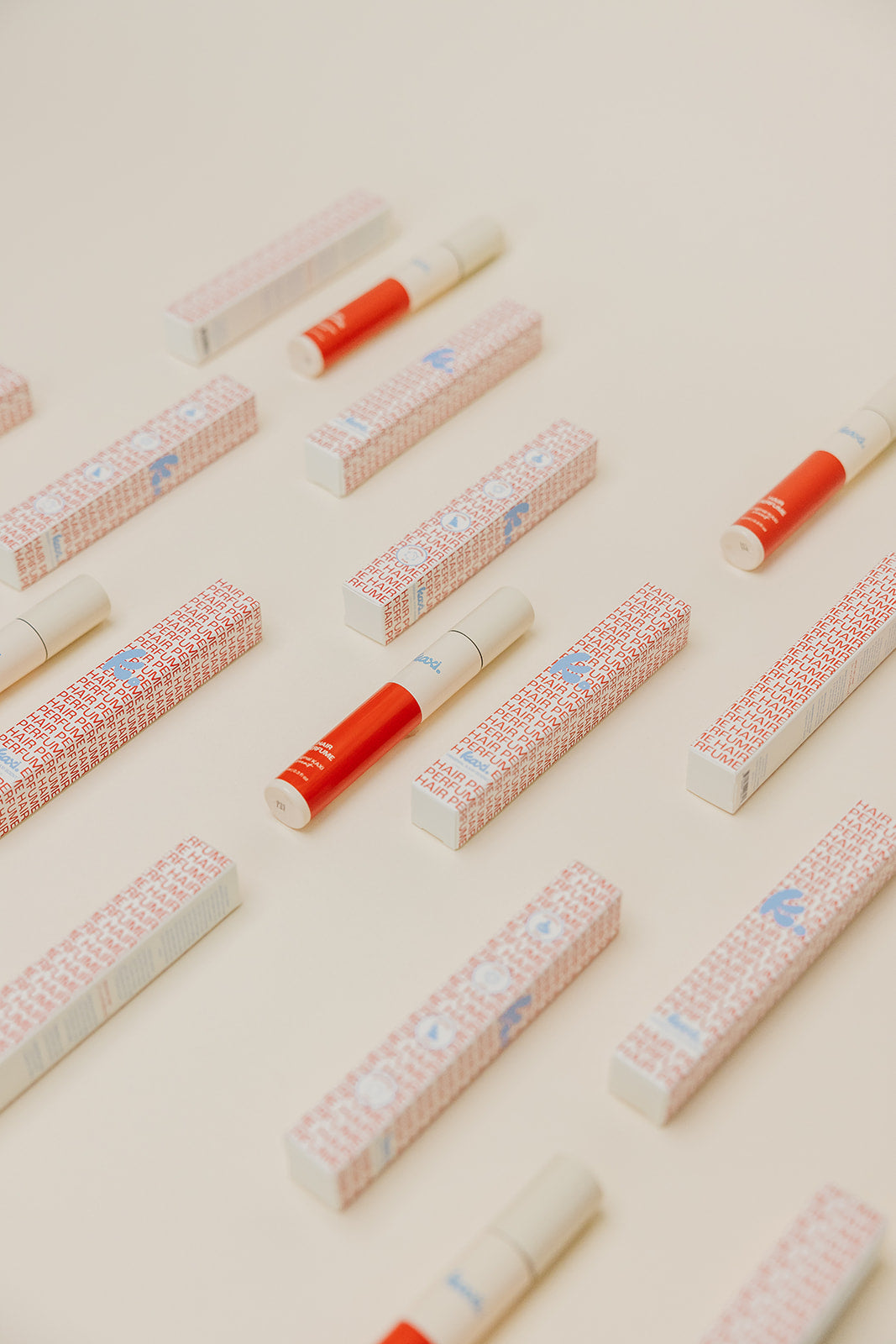 Multiple hair perfume spray tubes and boxes arranged in a scattered pattern