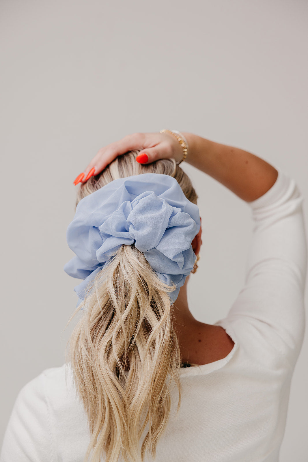 Large light blue scrunchie worn on blonde hair bun.