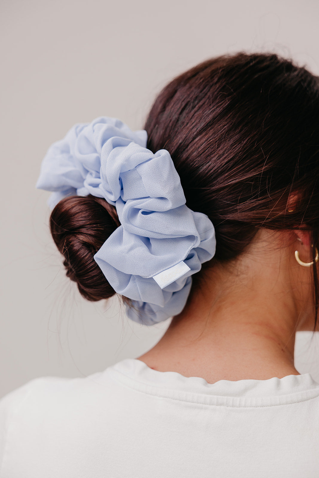 Large scrunchie with light blue ruffled fabric, worn in a low bun.