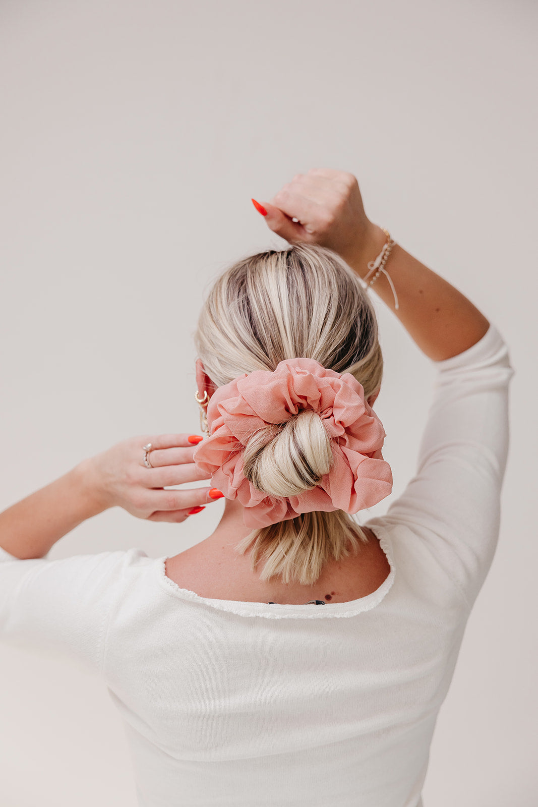 Jumbo scrunchie with coral pink ruffled flower on blonde hair bun