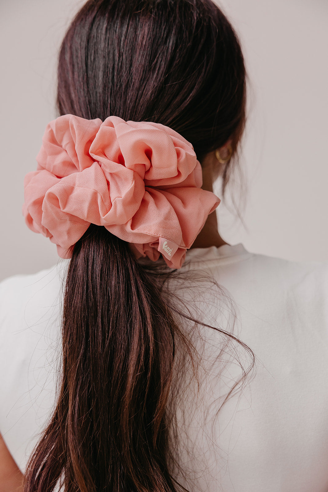 Jumbo scrunchie with coral pink ruffled flower on dark hair