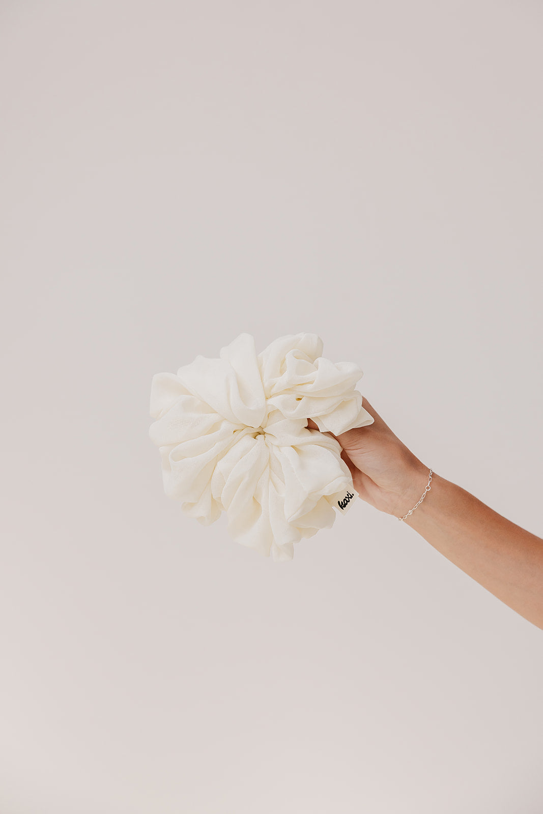 Ivory jumbo scrunchie held in hand with soft ruffled scrunch design