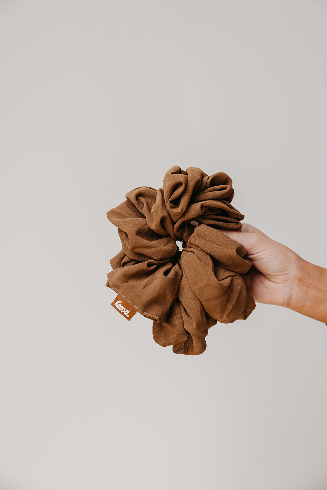 Brown jumbo scrunchie held in hand, large scrunched rosette