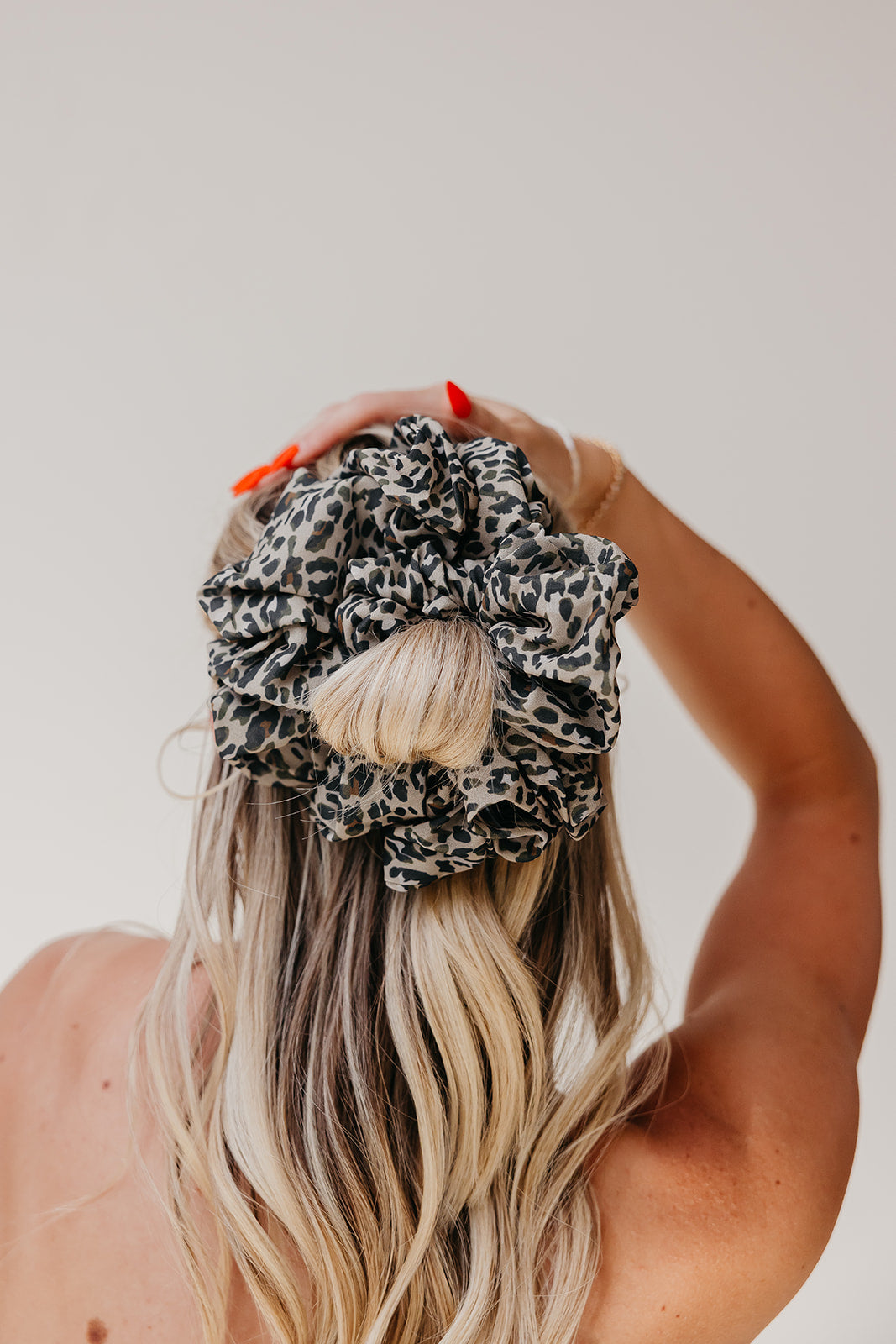 Jumbo scrunchie in leopard-print fabric on blonde hair bun.
