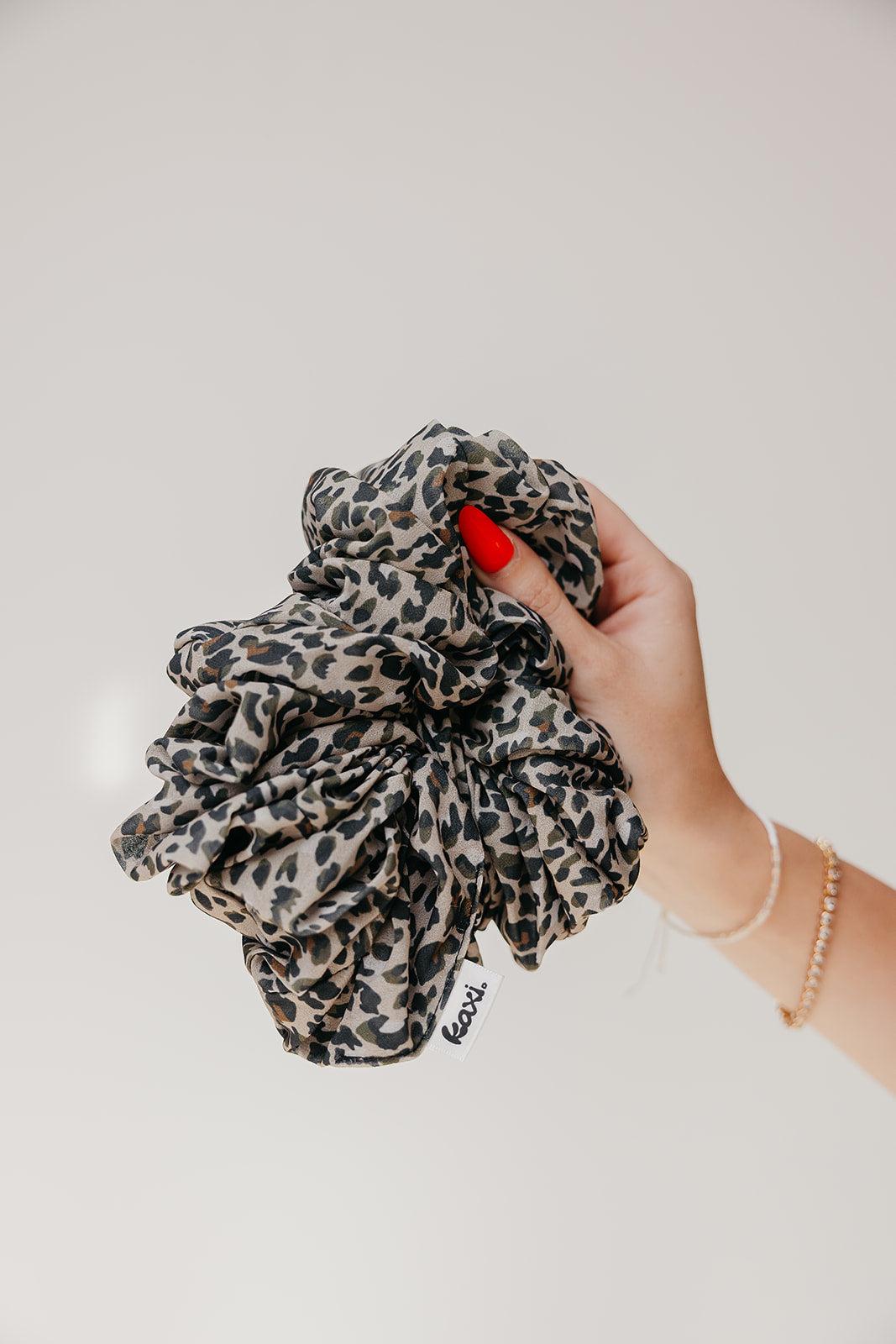 Large scrunchie with black-and-beige animal print fabric ruffle.