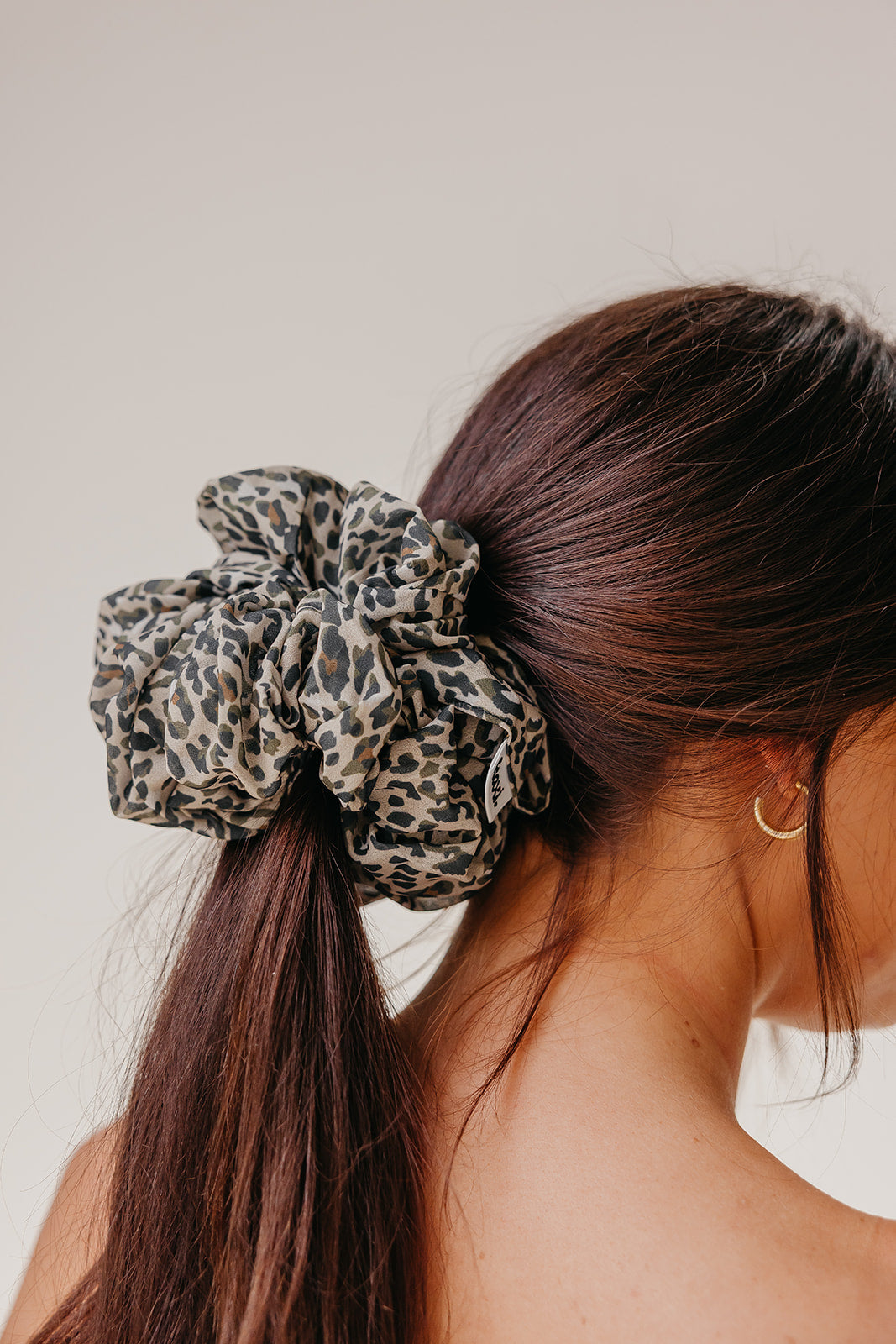 Jumbo scrunchie in leopard-print fabric in light brown and tan tones.