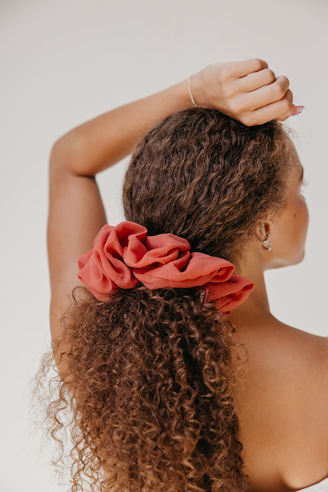 Jumbo scrunchie in red-orange with ruffled flower detail on curly hair