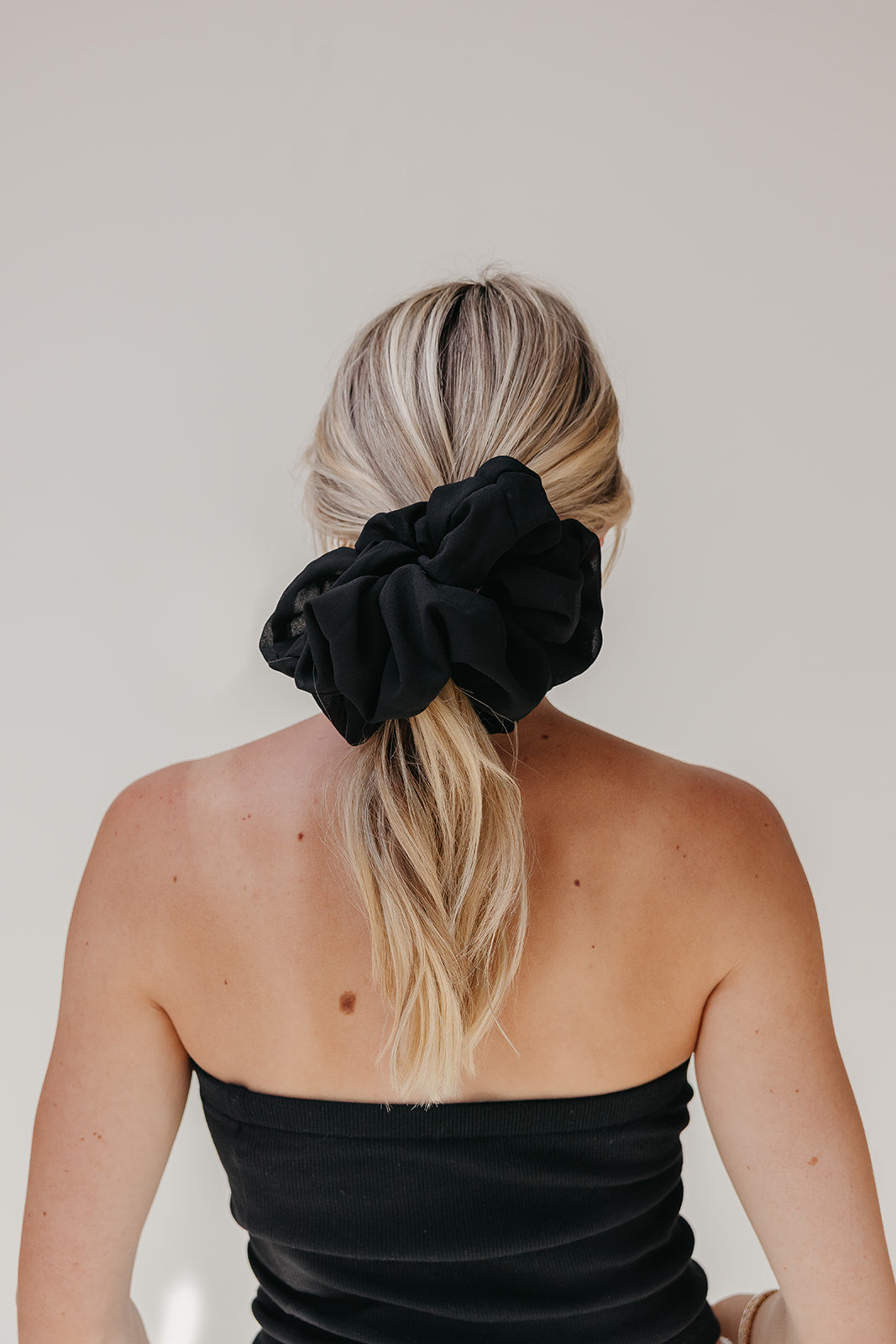 Black jumbo scrunchie on blonde hair in a high ponytail