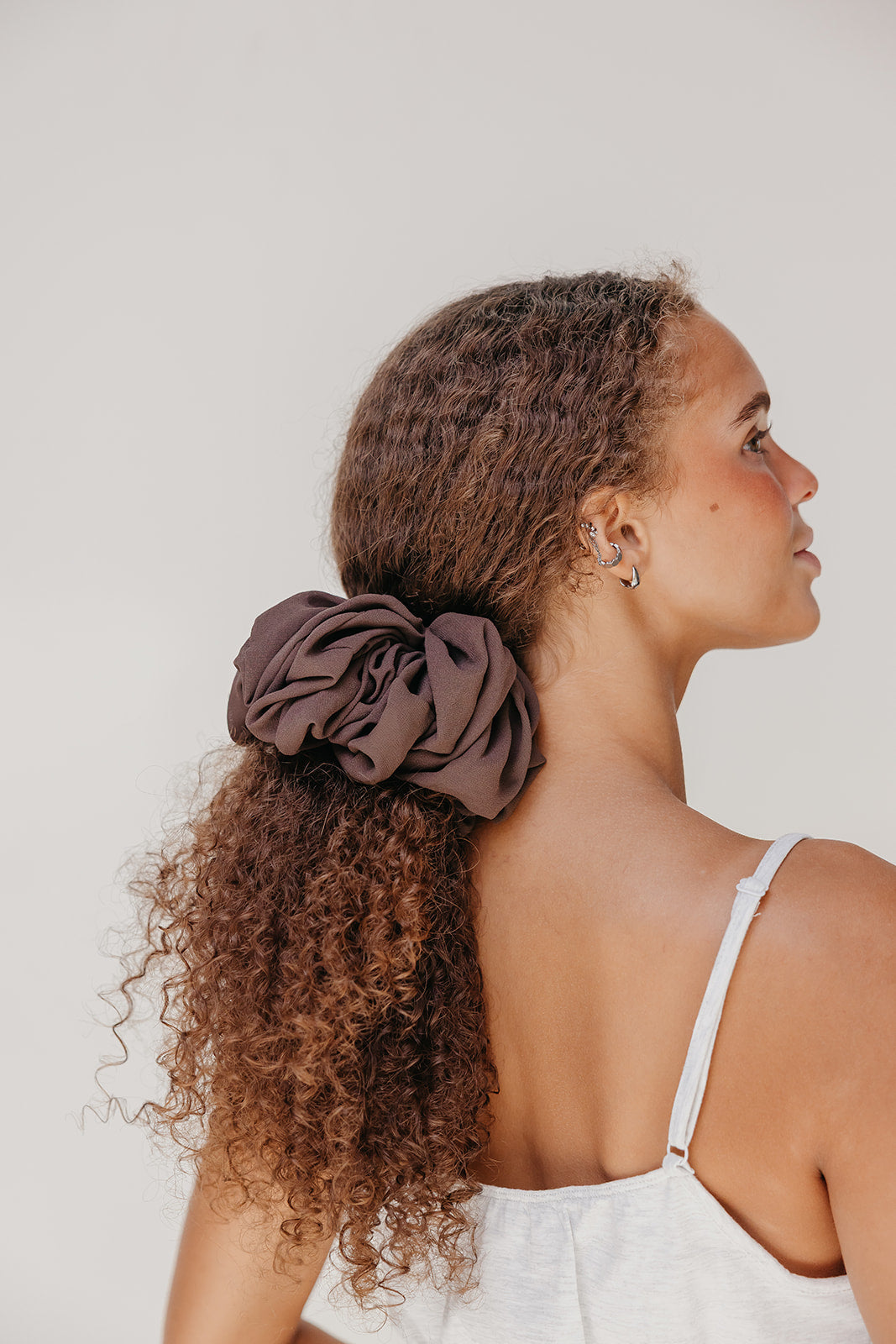 Jumbo scrunchie in dark brown on curly hair bun, ruffled scrunchie look.