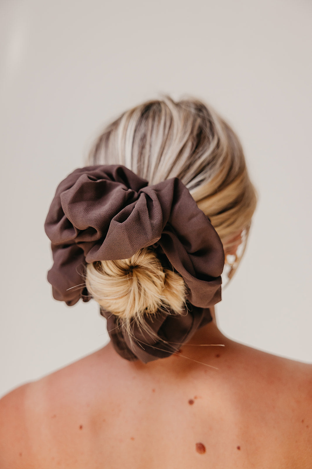 Jumbo scrunchie in dark brown fabric, gathered ruffle on hair.