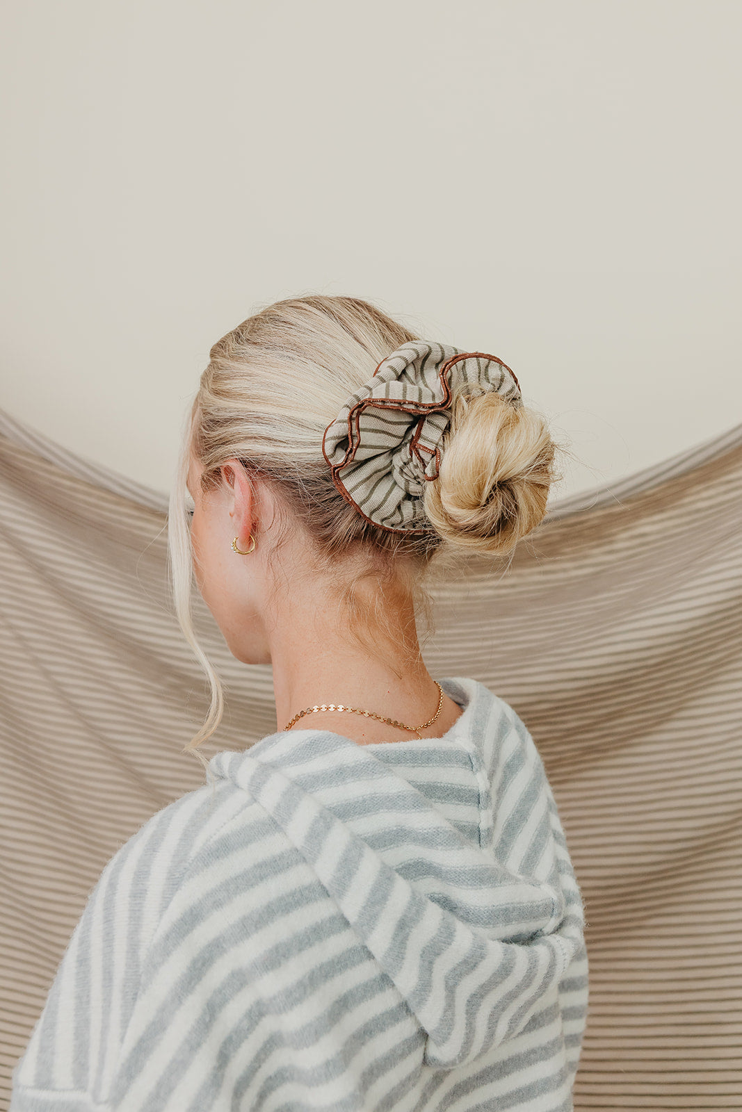 Tan and brown striped corset-style scrunchie on blonde hair bun from side