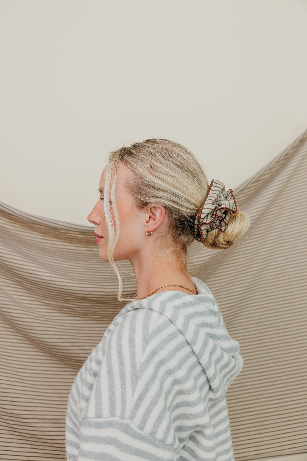 Striped corset scrunchie on hair, dark tan and maroon stripes, gathered ruffle.